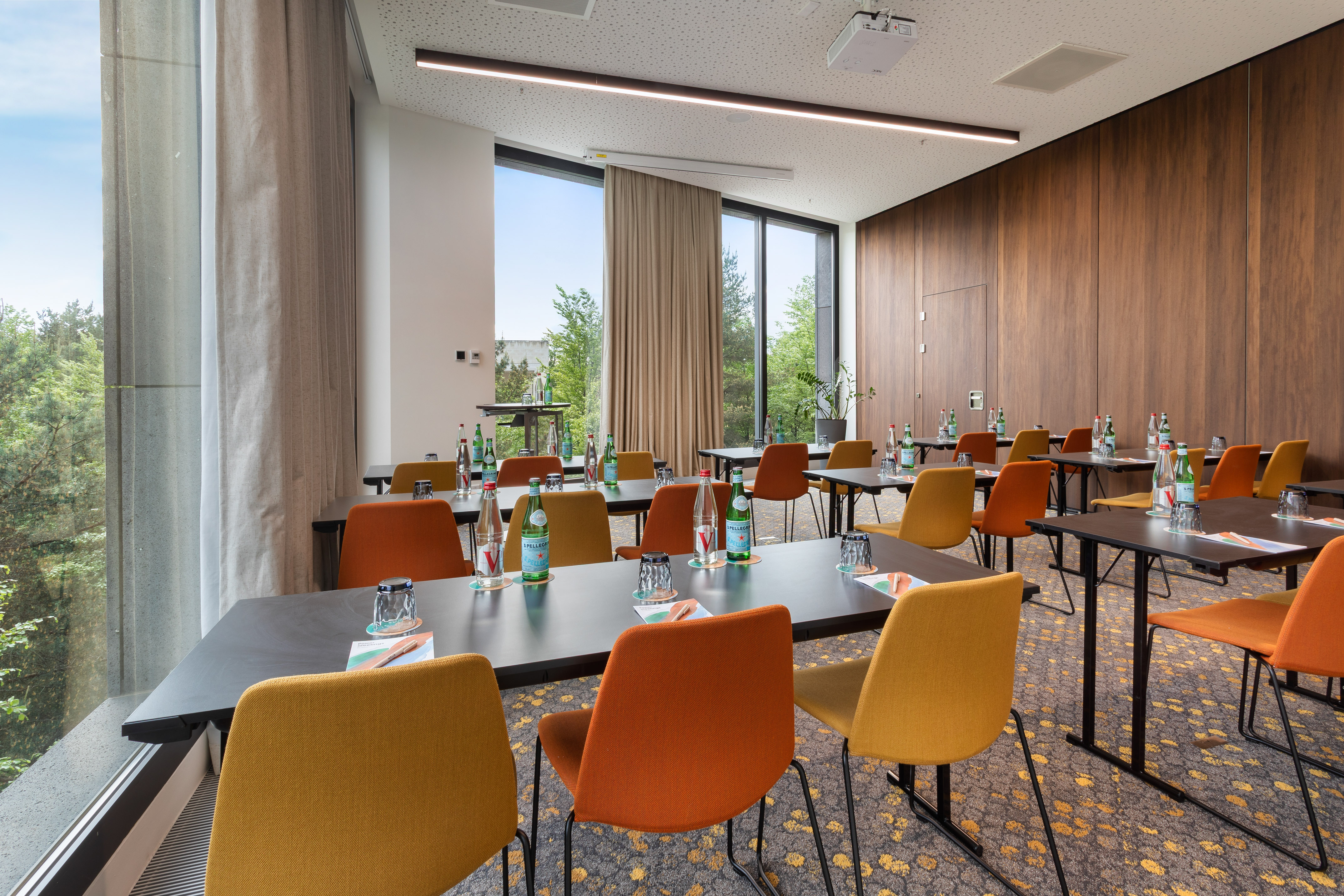 Bright conference room with large windows, colorful chairs, and projector setup.