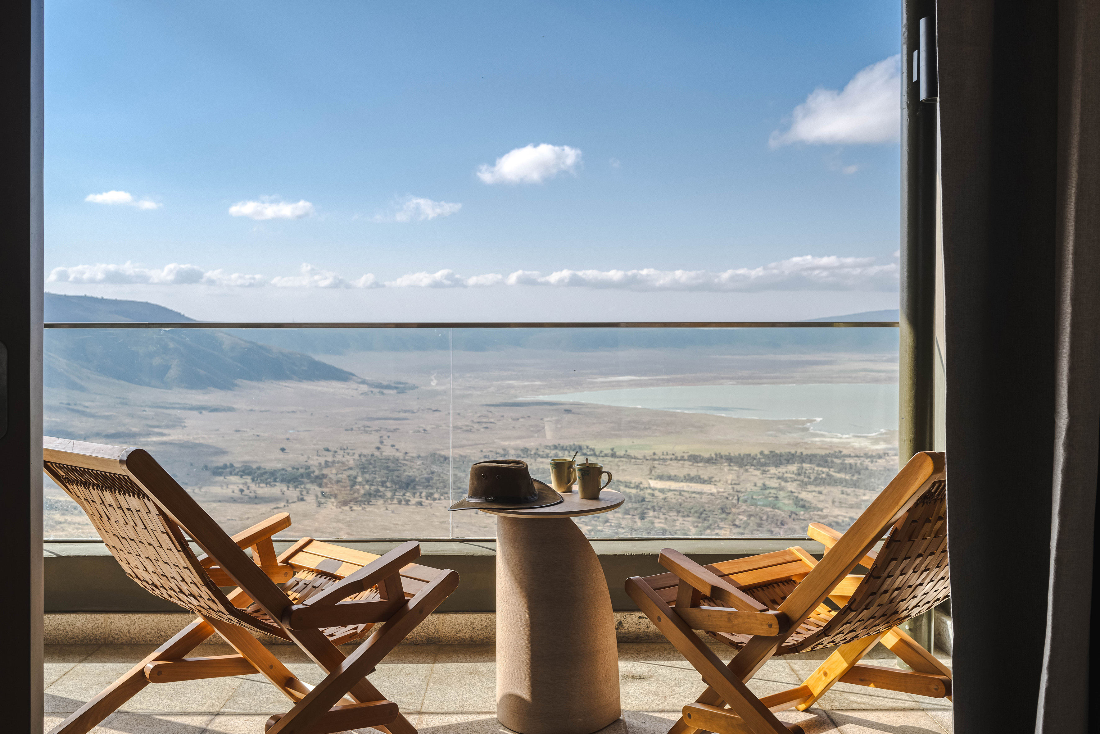 Scenic Ngorongoro Crater balcony view with chairs, hat, and mugs.