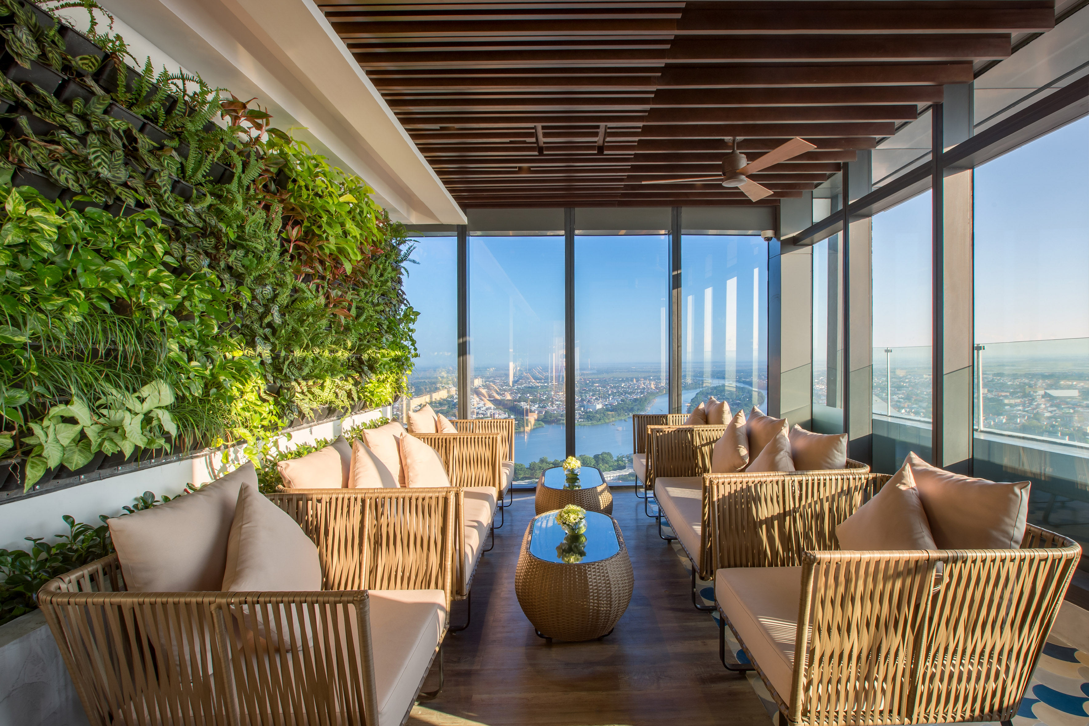 Rooftop lounge with vertical garden, wicker sofas, and panoramic city views.