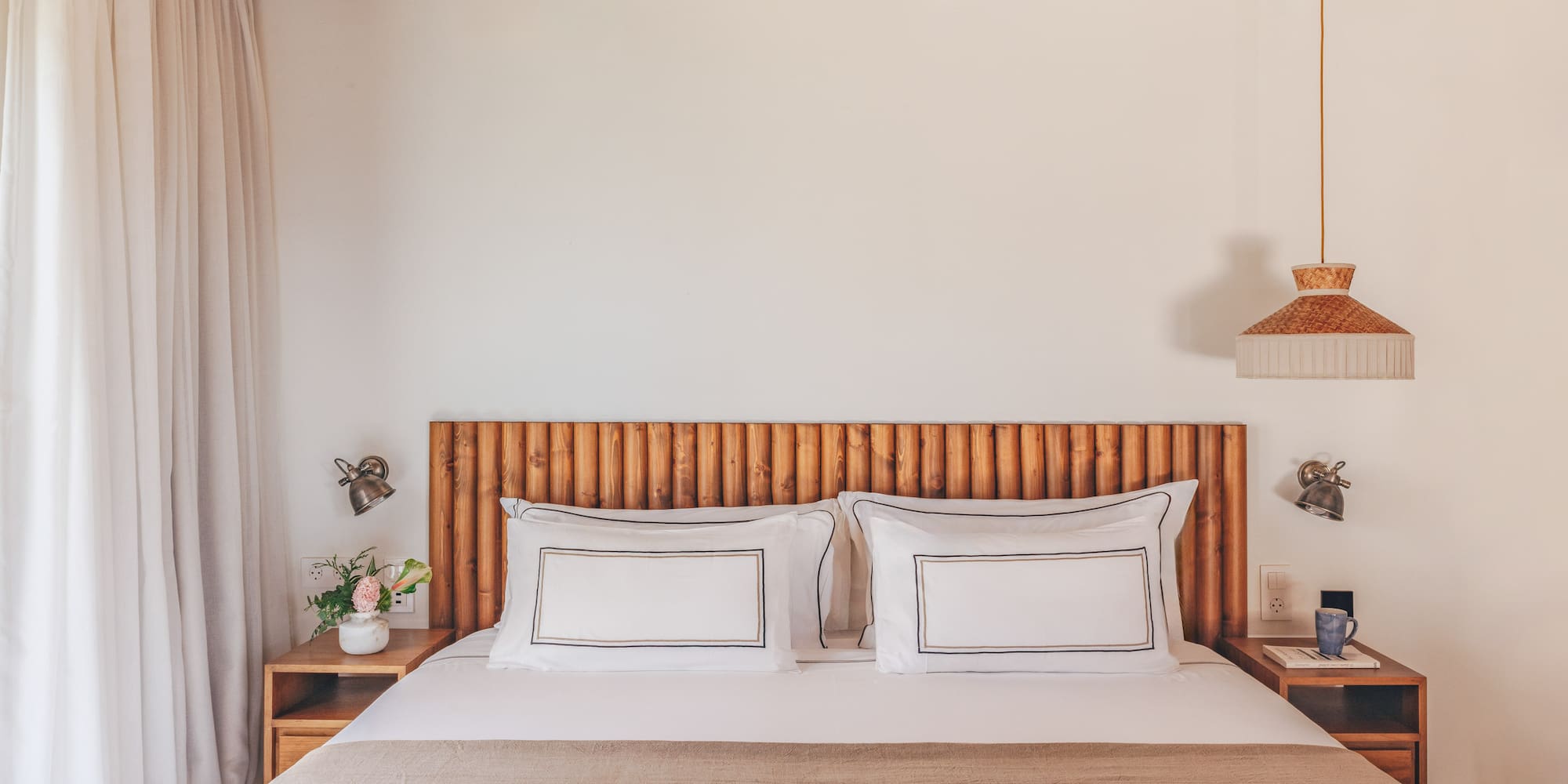 Cozy bedroom with wooden headboard, bamboo ceiling, white bed, and natural decor.