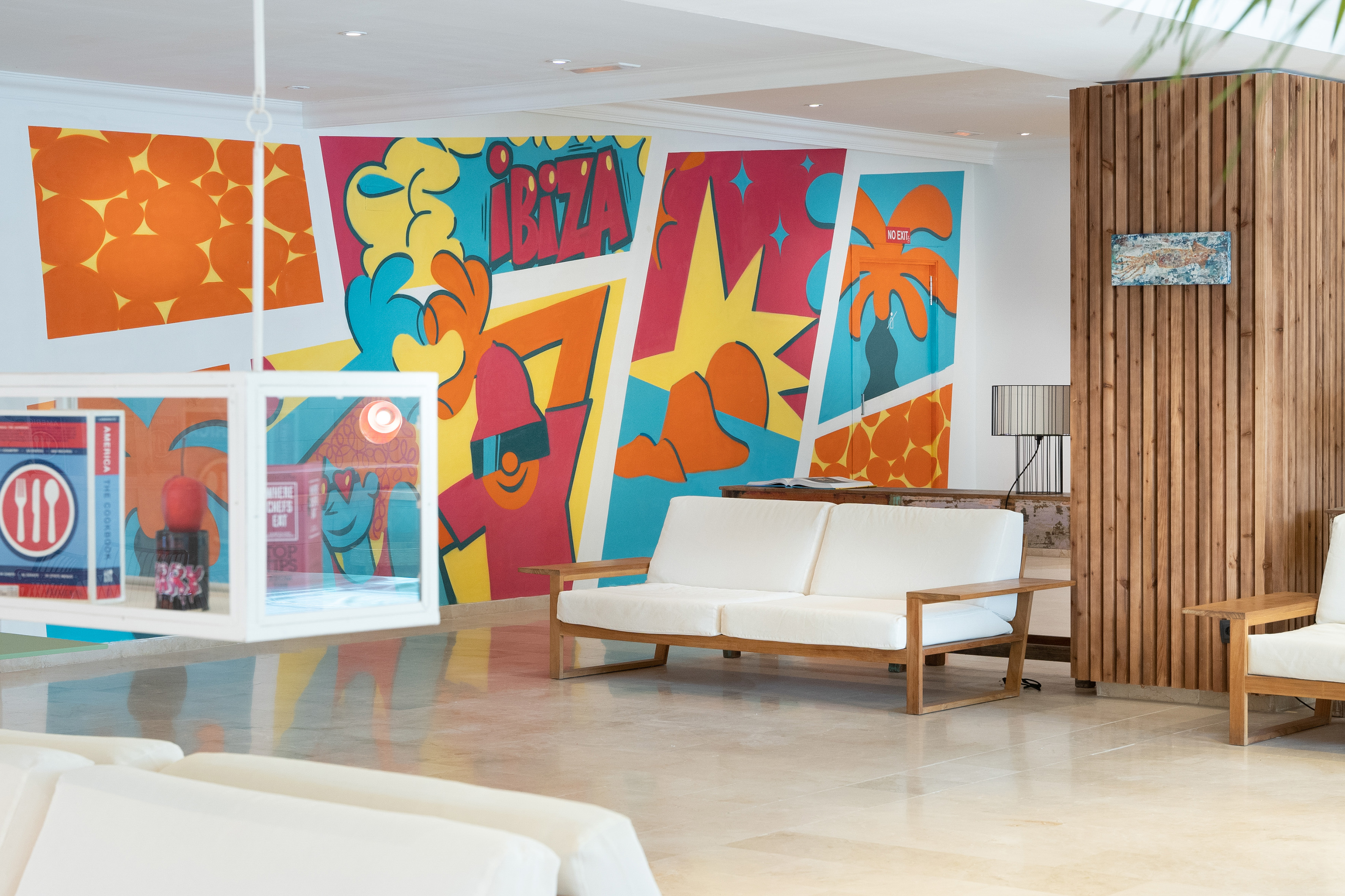 Vibrant Ibiza pop art mural in a stylish hotel lobby with modern white sofas.