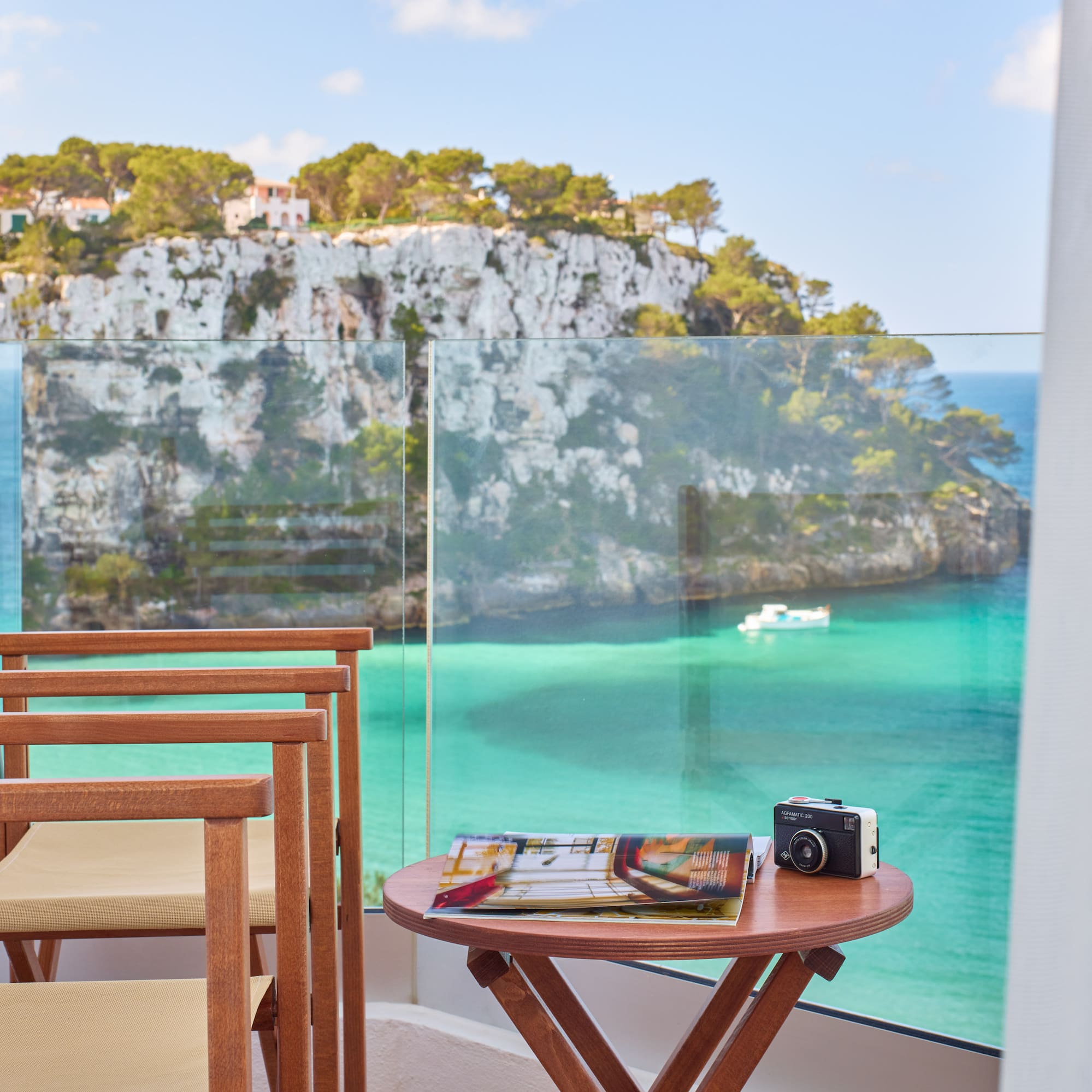 a table and chairs with a camera on a balcony overlooking a body of water