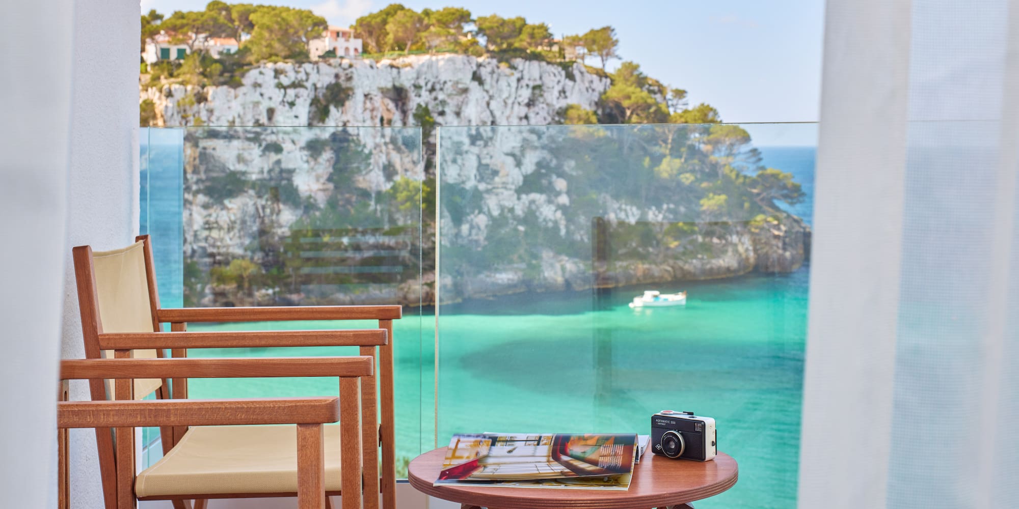 a table and chairs with a camera on a balcony overlooking a body of water