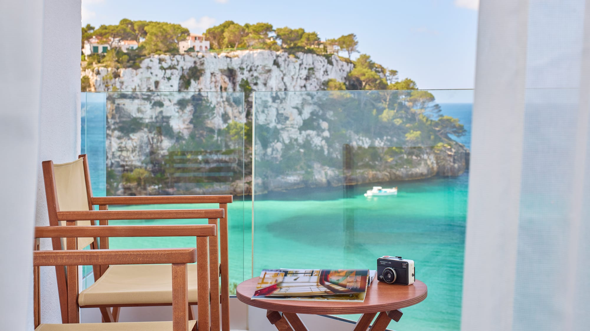 a table and chairs with a camera on a balcony overlooking a body of water