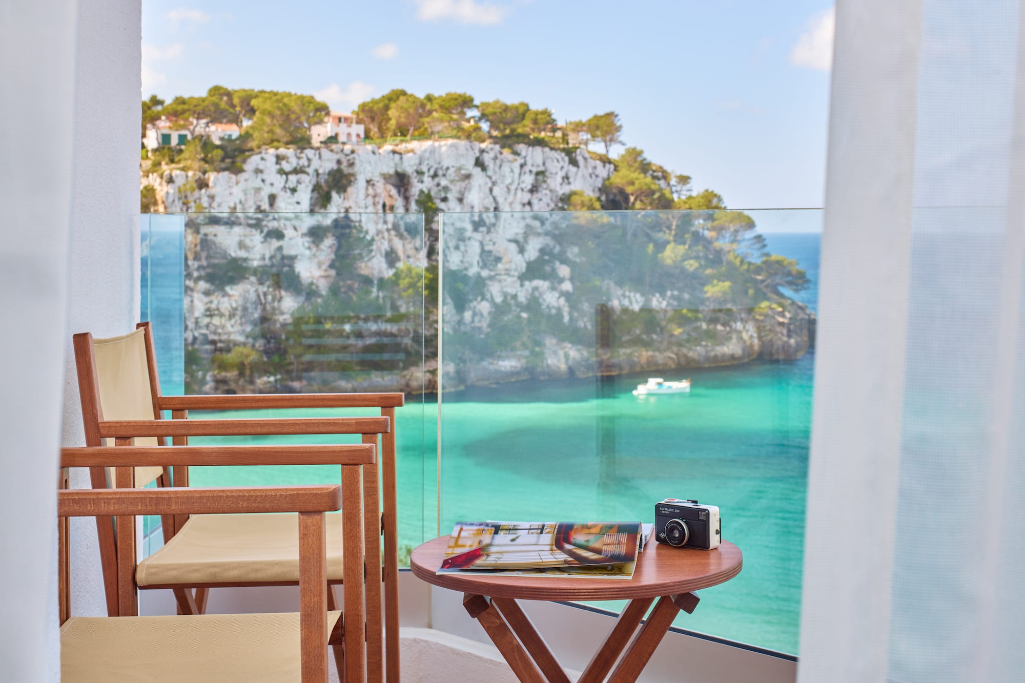 a table and chairs with a camera on a balcony overlooking a body of water