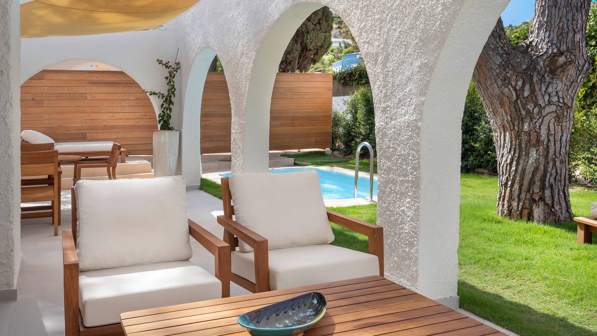 a patio with white chairs and a table