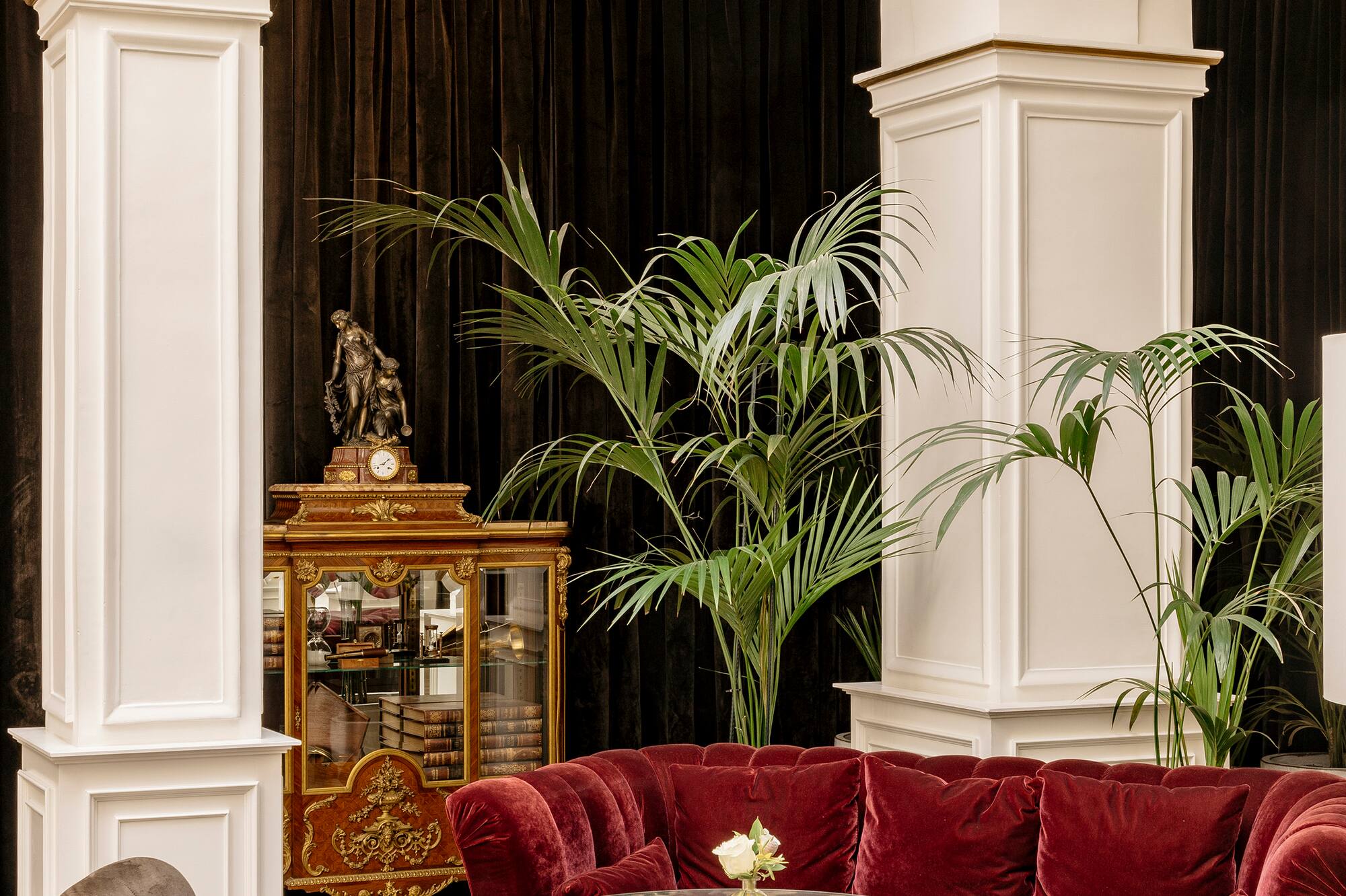 Elegant hotel lobby with red velvet sofa, classic arches, and ornate decor.