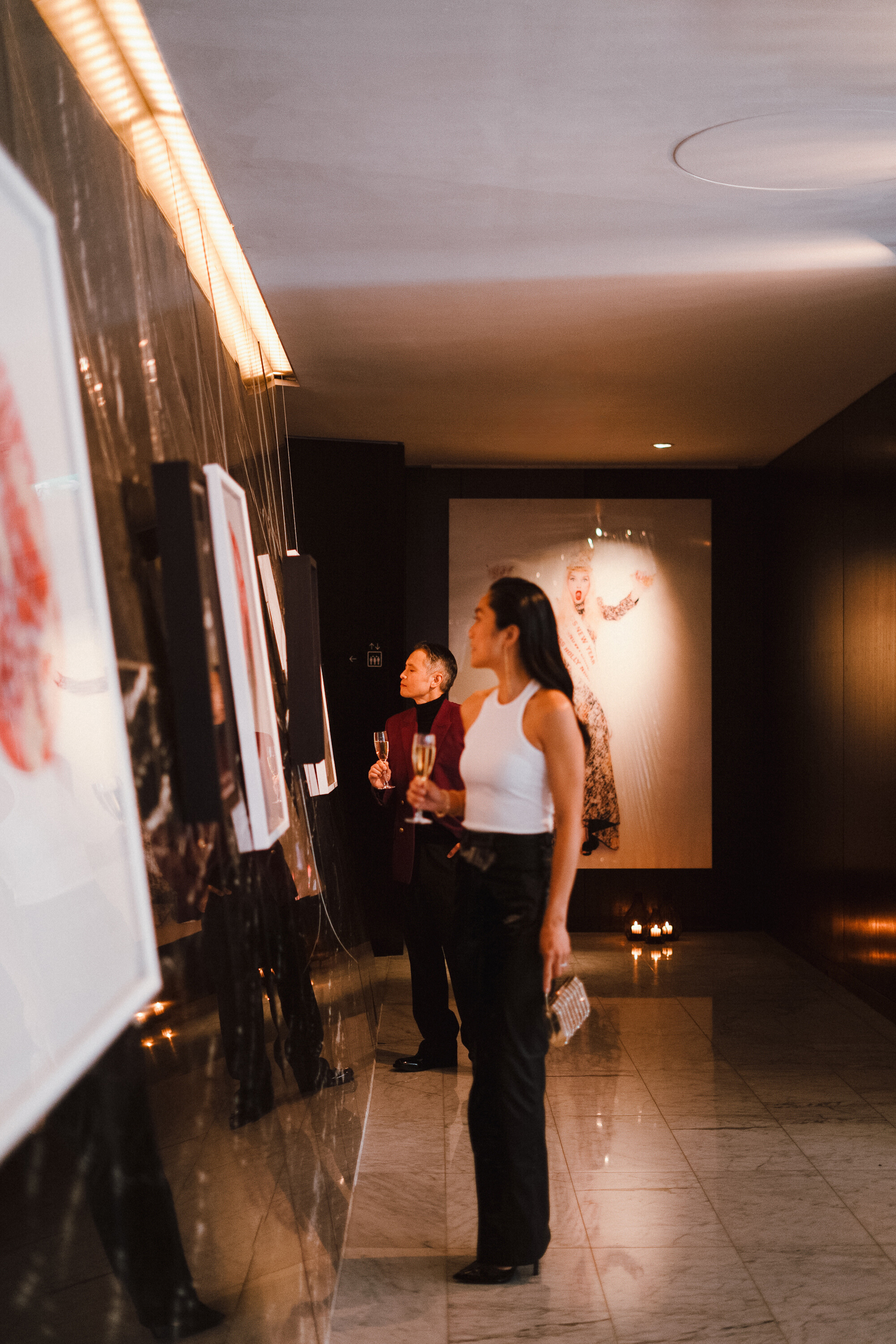 A man and a woman are examining the pictures on the wall.