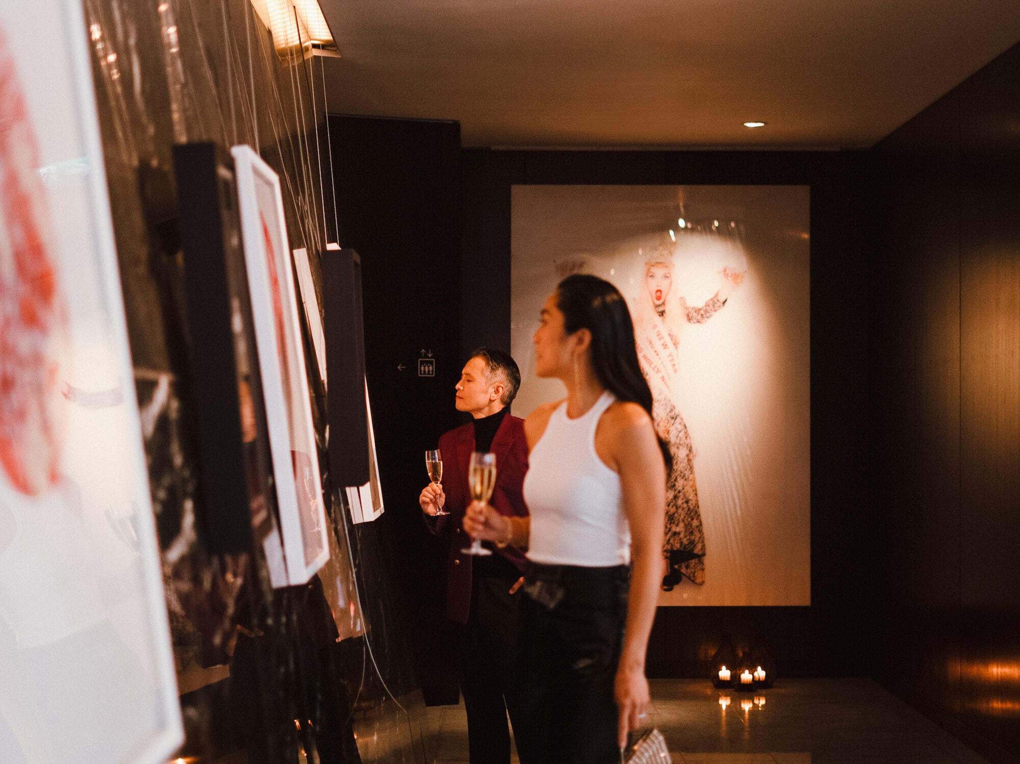 A man and a woman are examining the pictures on the wall.