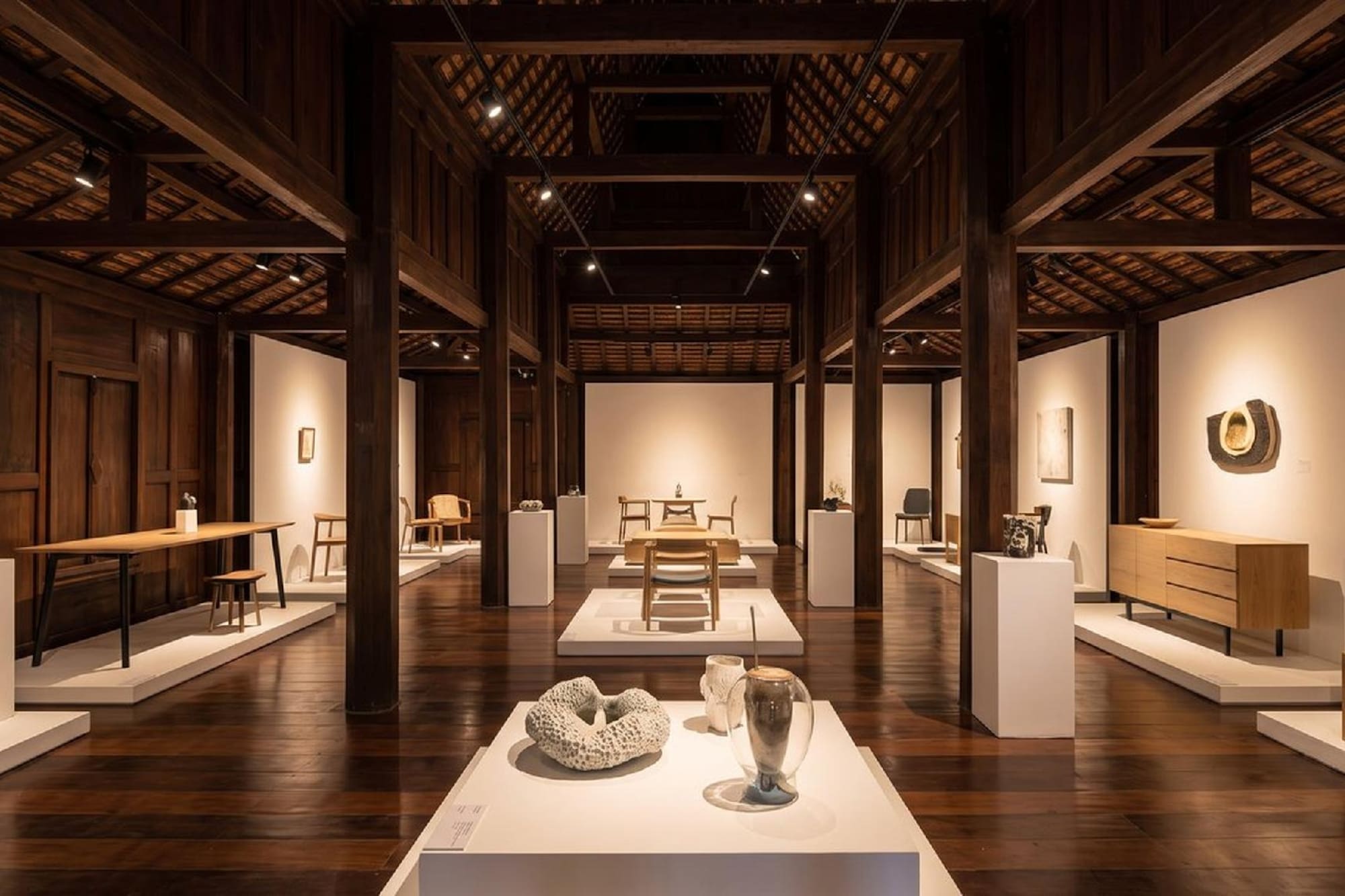 Modern furniture and art exhibition in a dark wooden gallery interior.