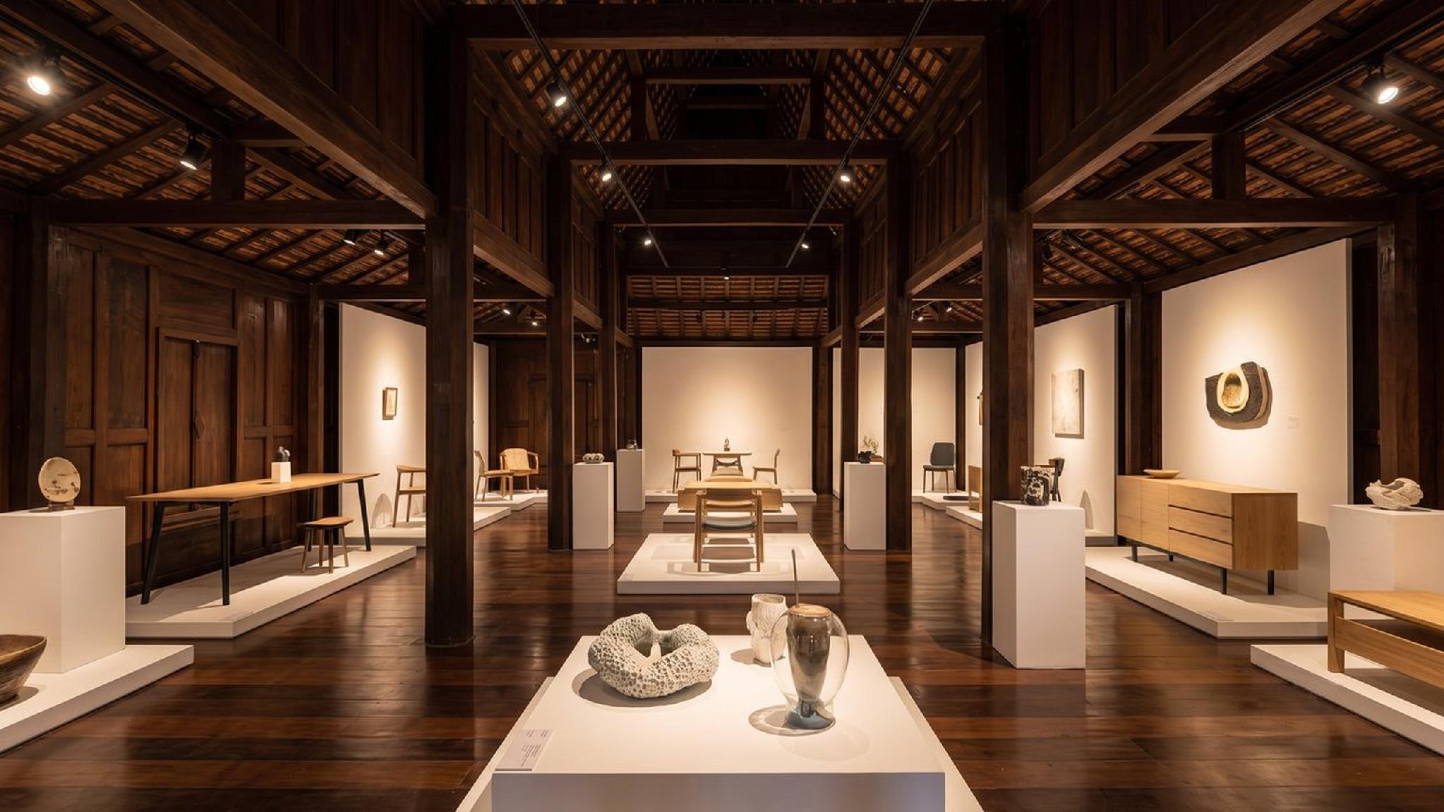 Modern furniture and art exhibition in a dark wooden gallery interior.