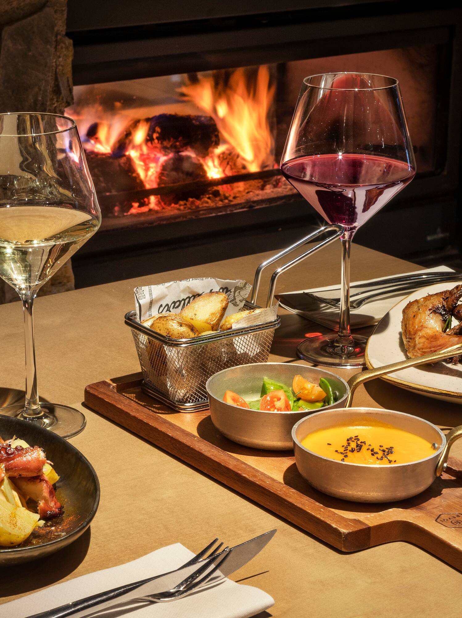 Cozy dinner with grilled octopus, roasted poultry, wine, and warm fireplace.