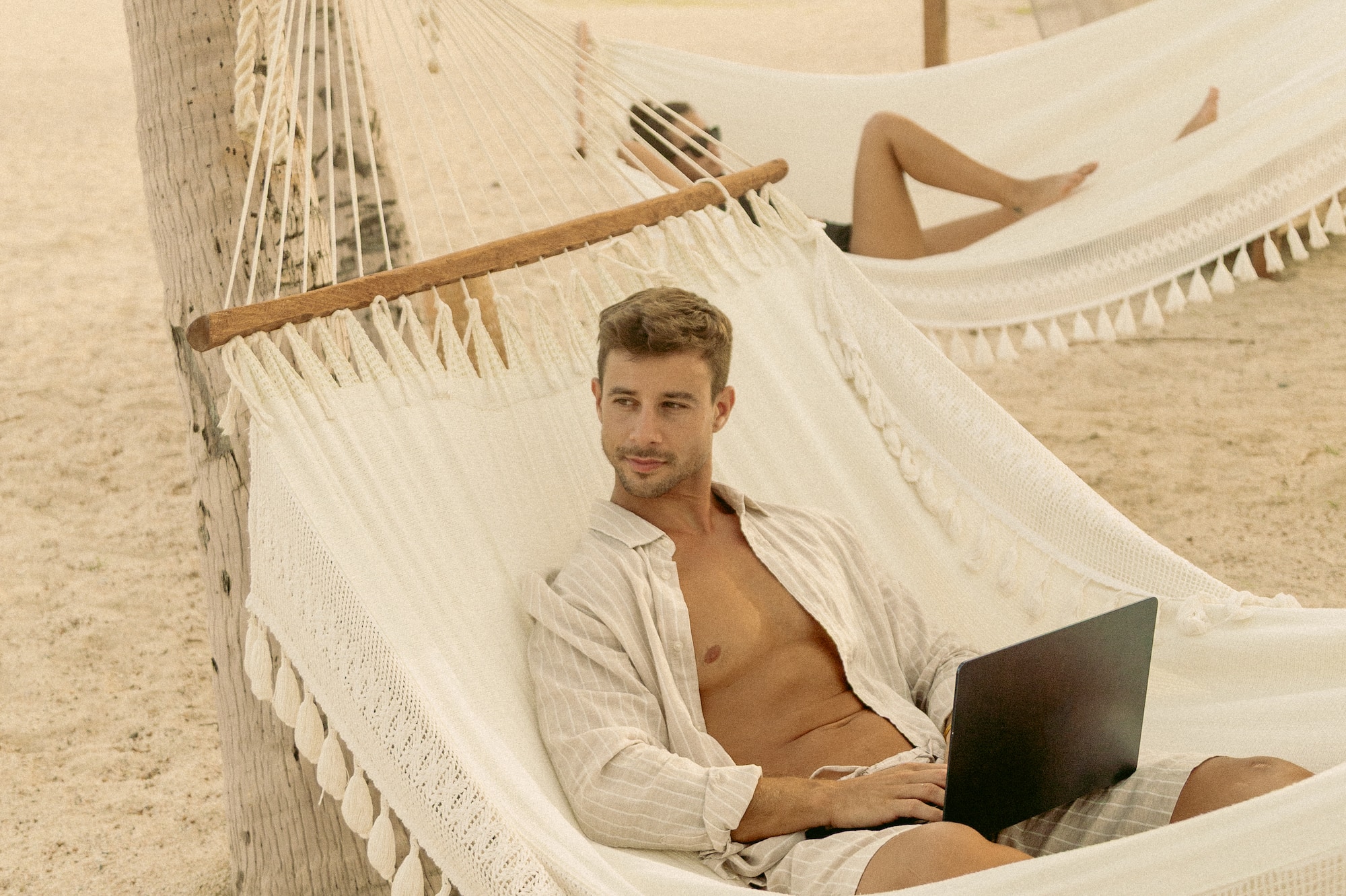 a man sitting in a hammock with a laptop