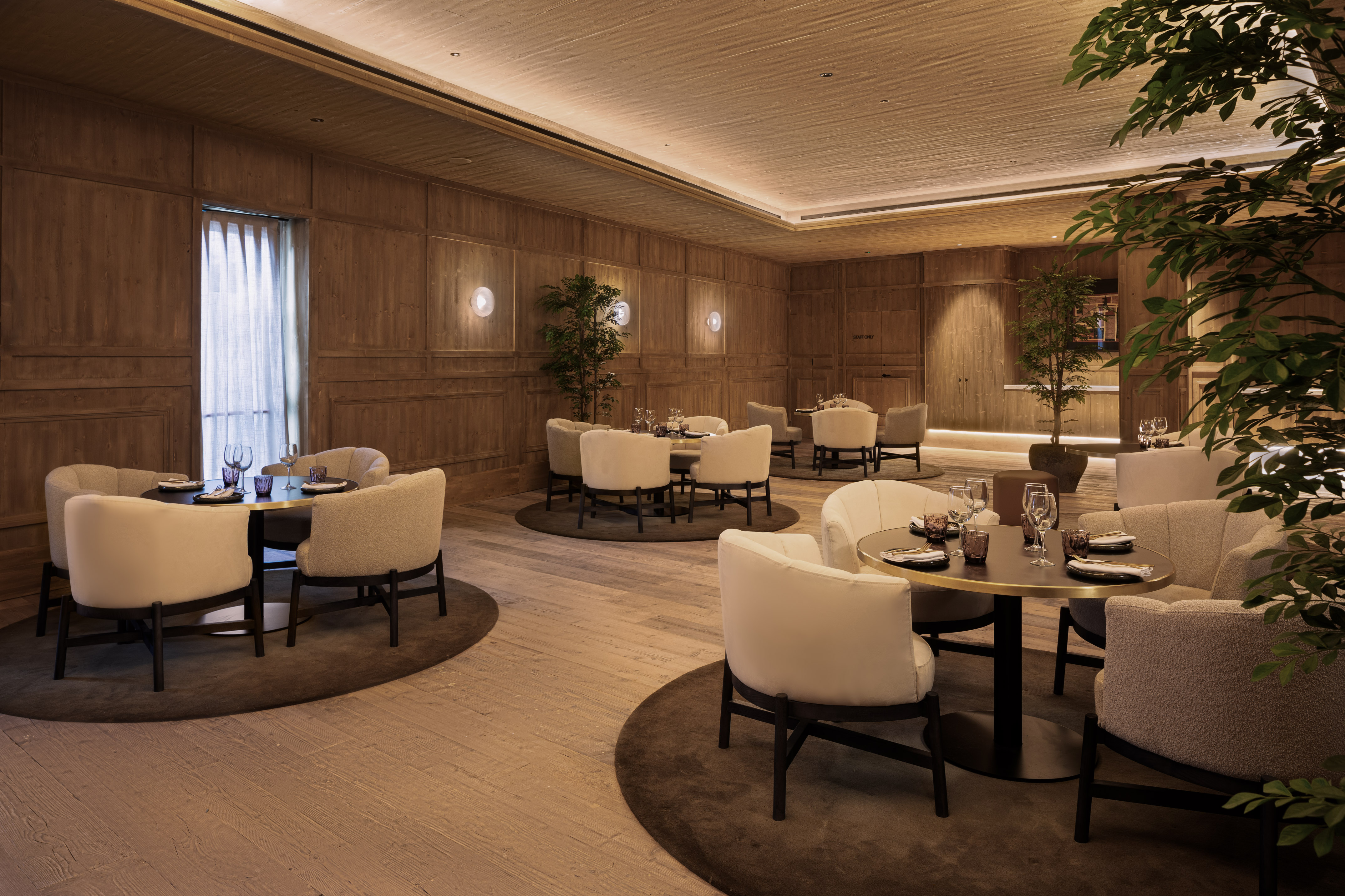 Elegant restaurant dining room featuring wood panels, plush seating, and warm lighting.