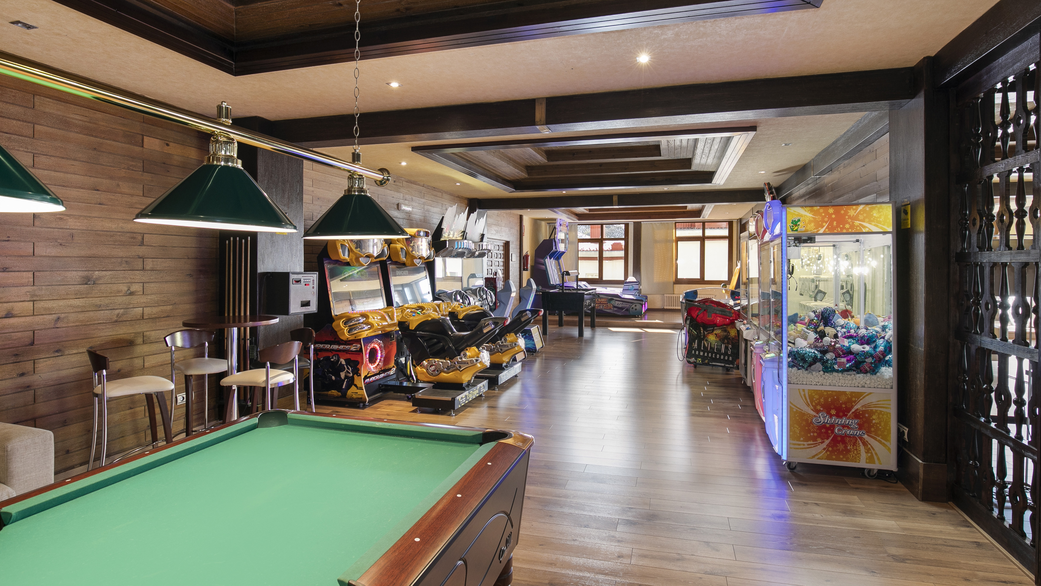 Entertainment game room featuring a billiards table, arcade machines, and claw games.
