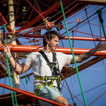 a man in a harness on a rope structure
