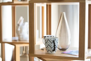 a white vase and a cup on a shelf
