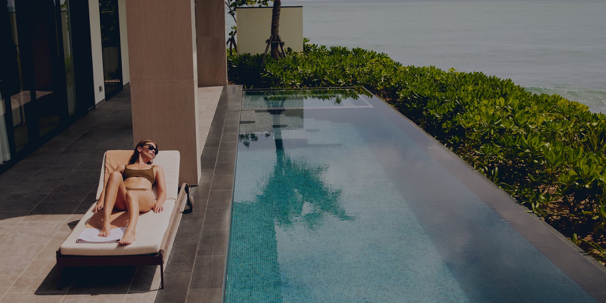 a woman lying on a lounge chair next to a pool