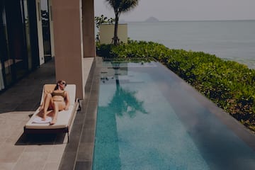 a woman lying on a lounge chair next to a pool