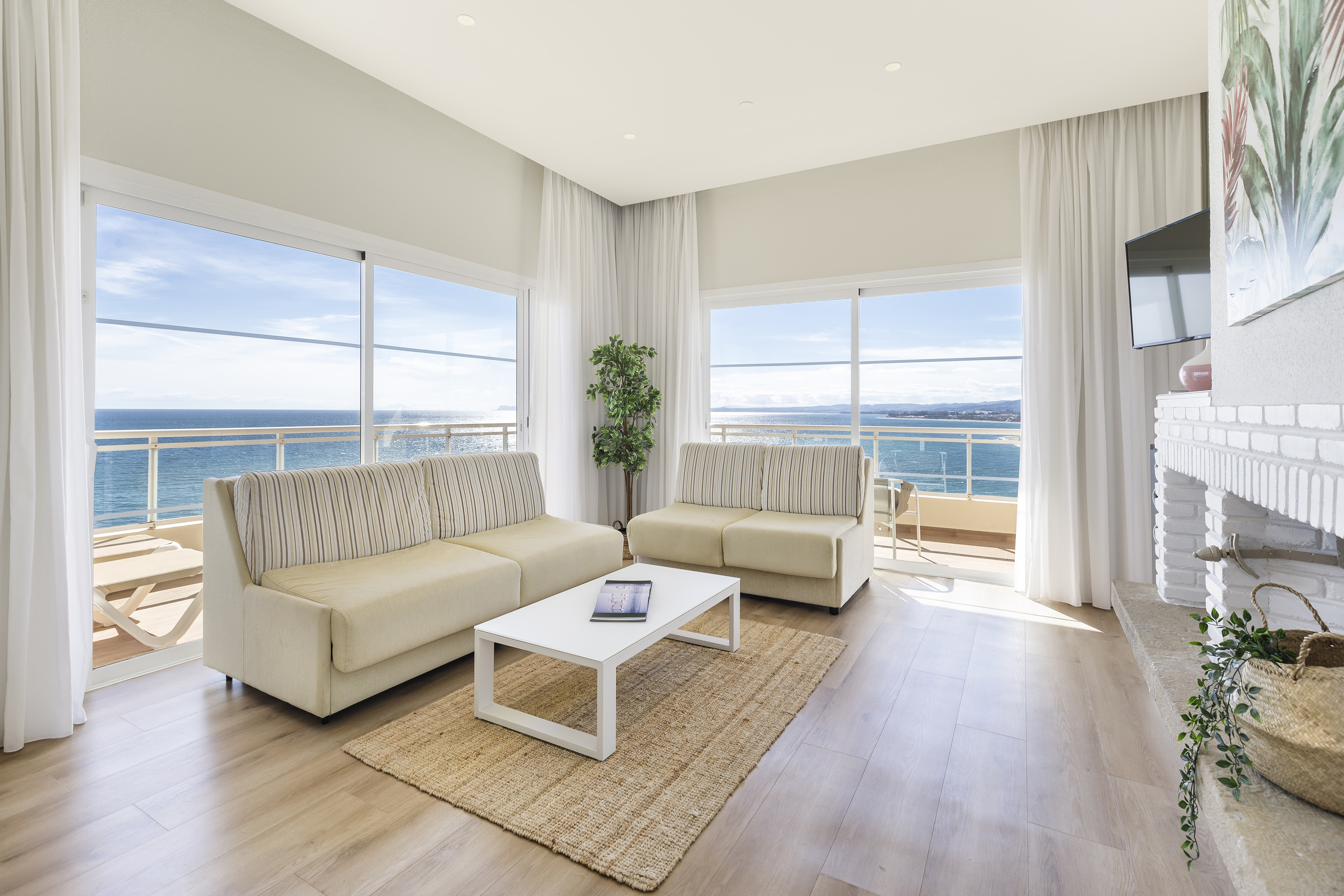 Coastal living room with ocean view, two sofas, white coffee table.