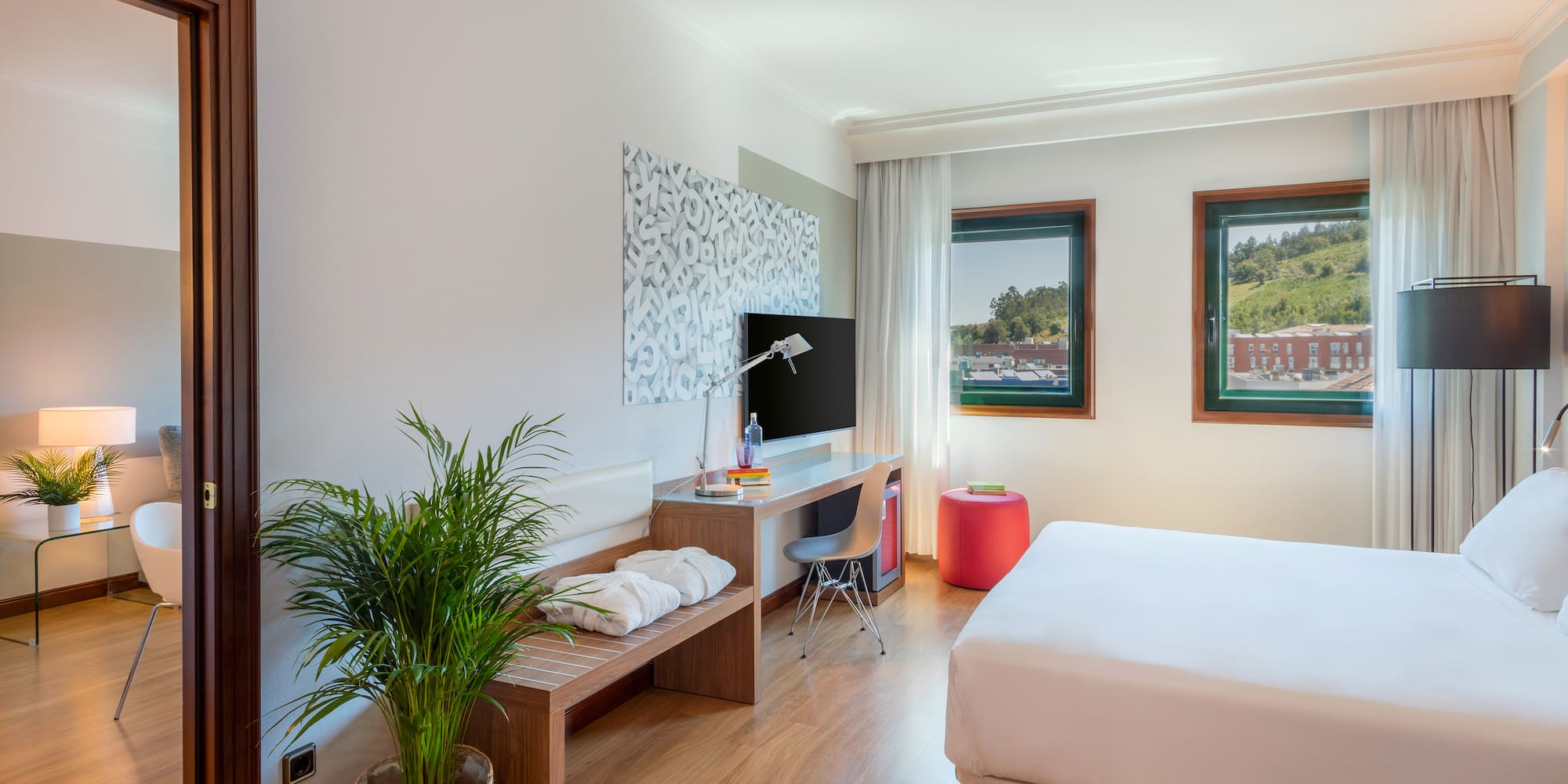 a room with a bed and a desk and a plant