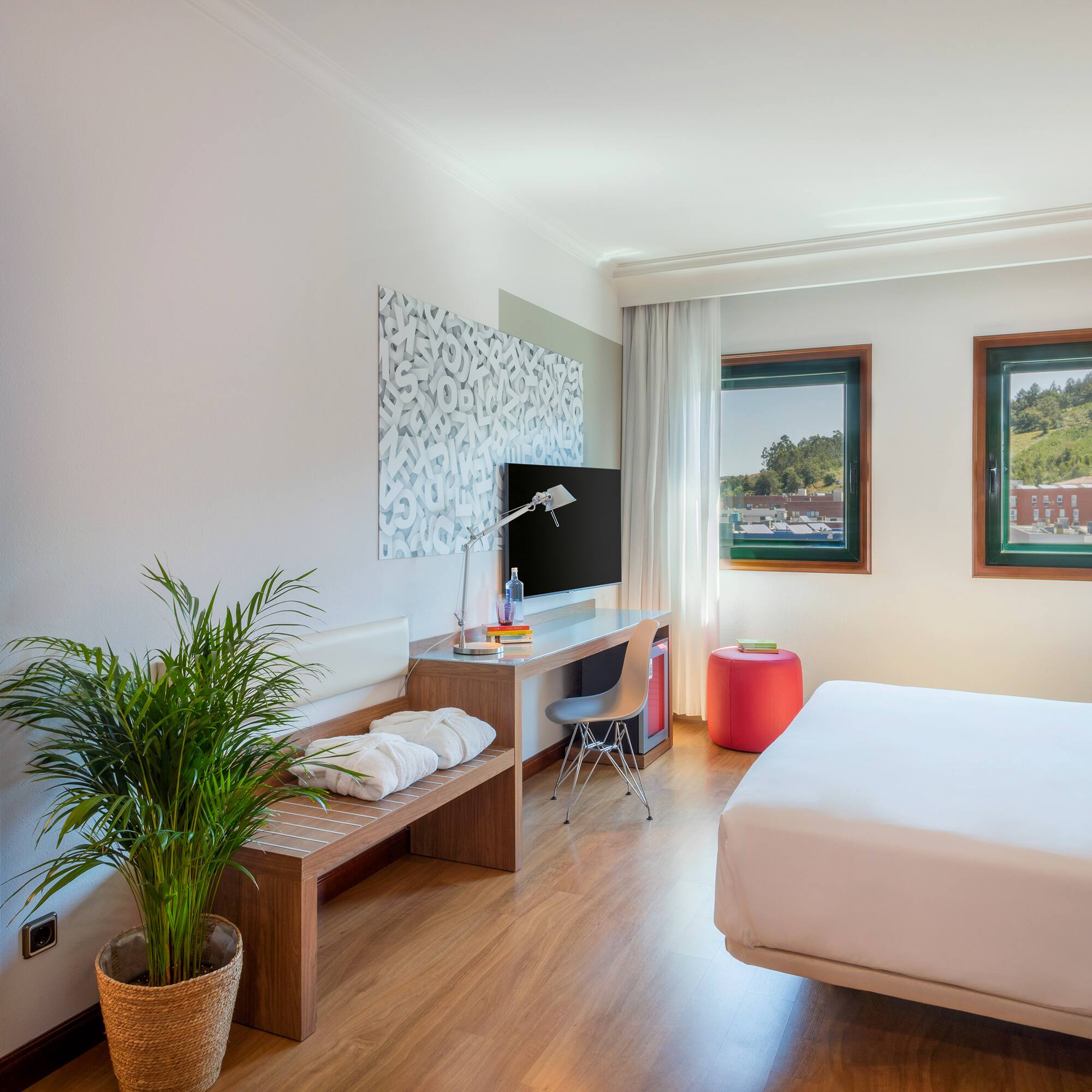 a room with a bed and a desk and a plant