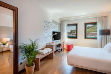 a room with a bed and a desk and a plant