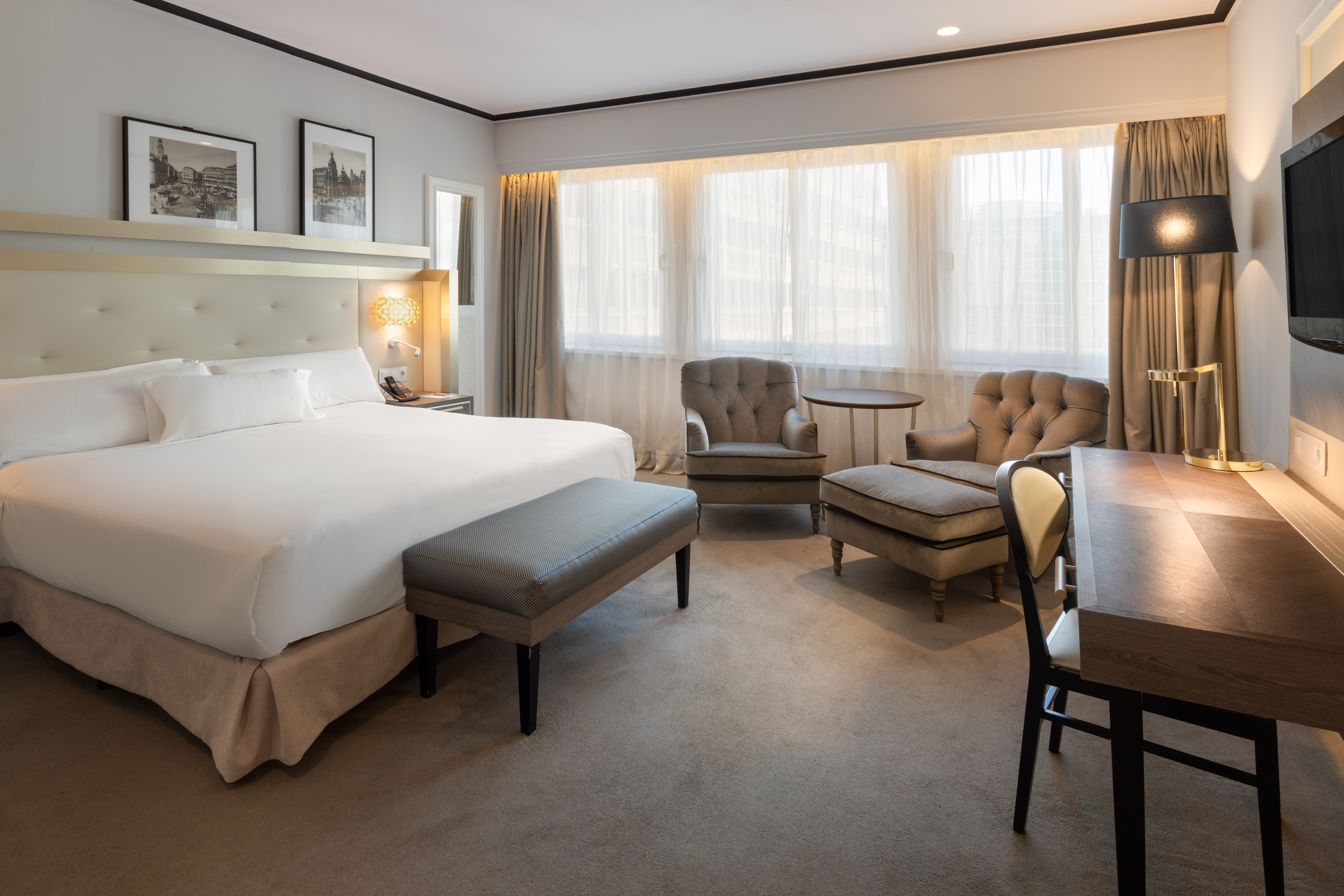 Elegant hotel guest room with large bed, plush seating, and work desk.