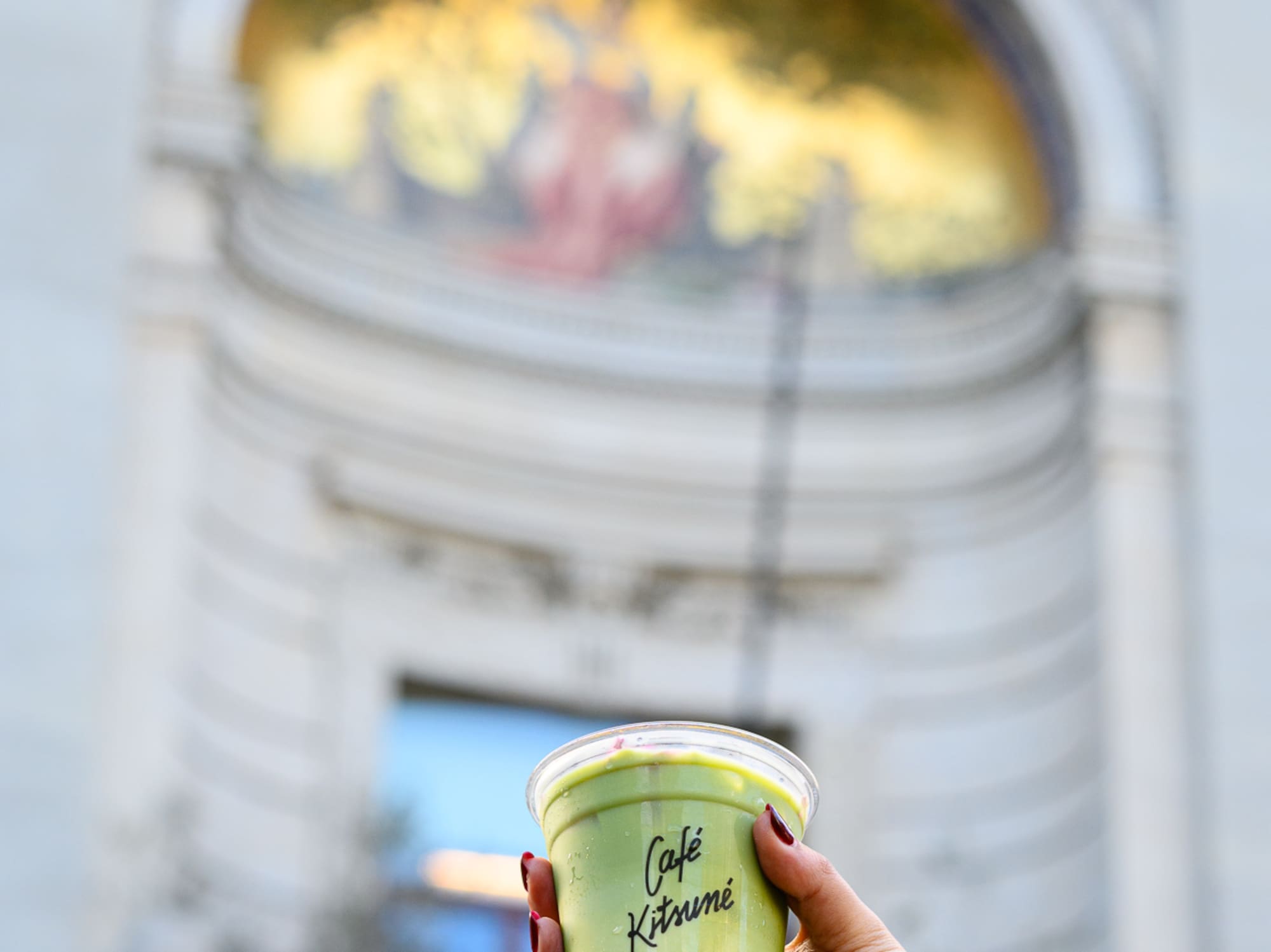 a hand holding a cup of green liquid