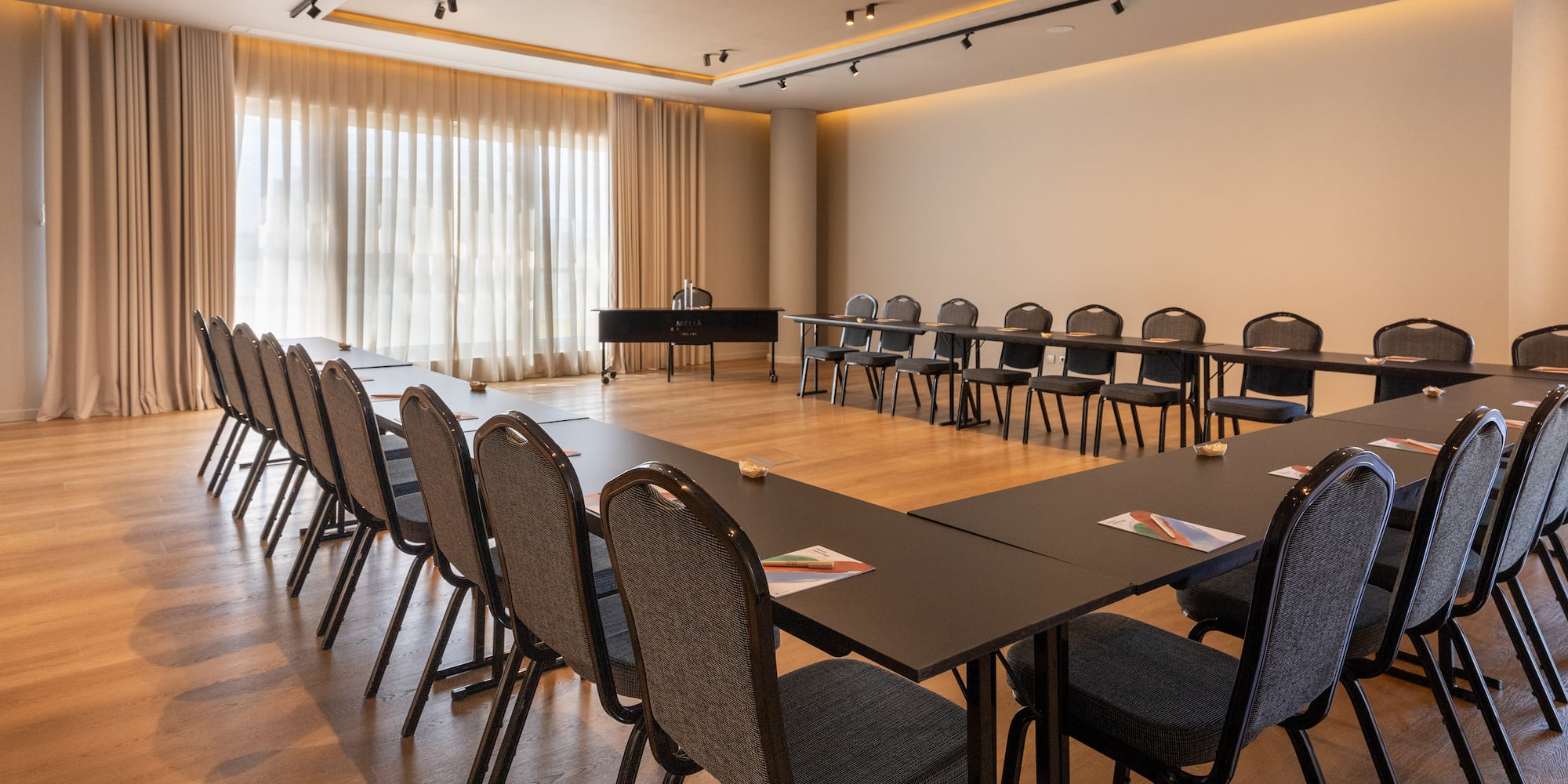 Modern hotel conference room with U-shape table setup and chairs.