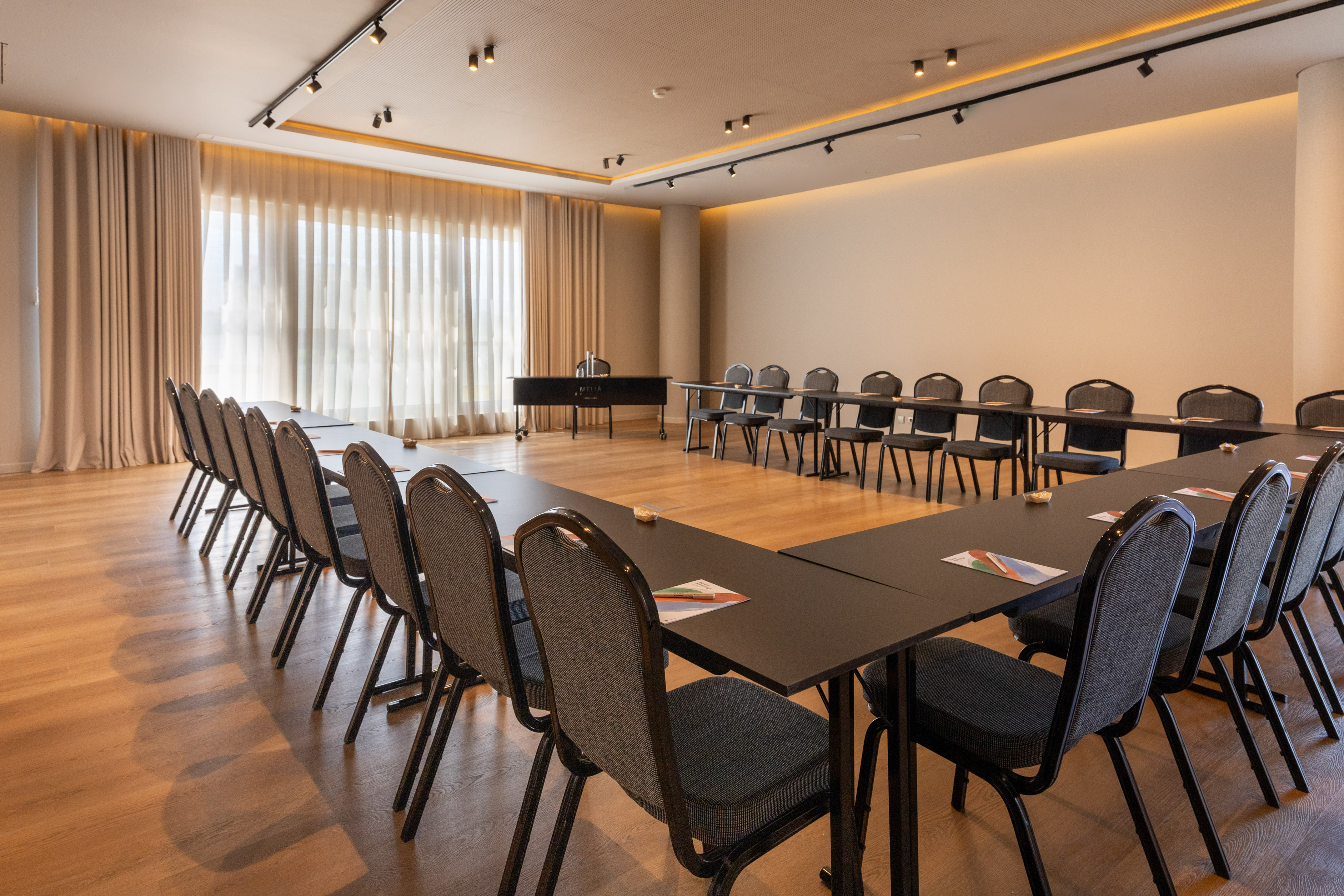 Modern hotel conference room with U-shape table setup and chairs.