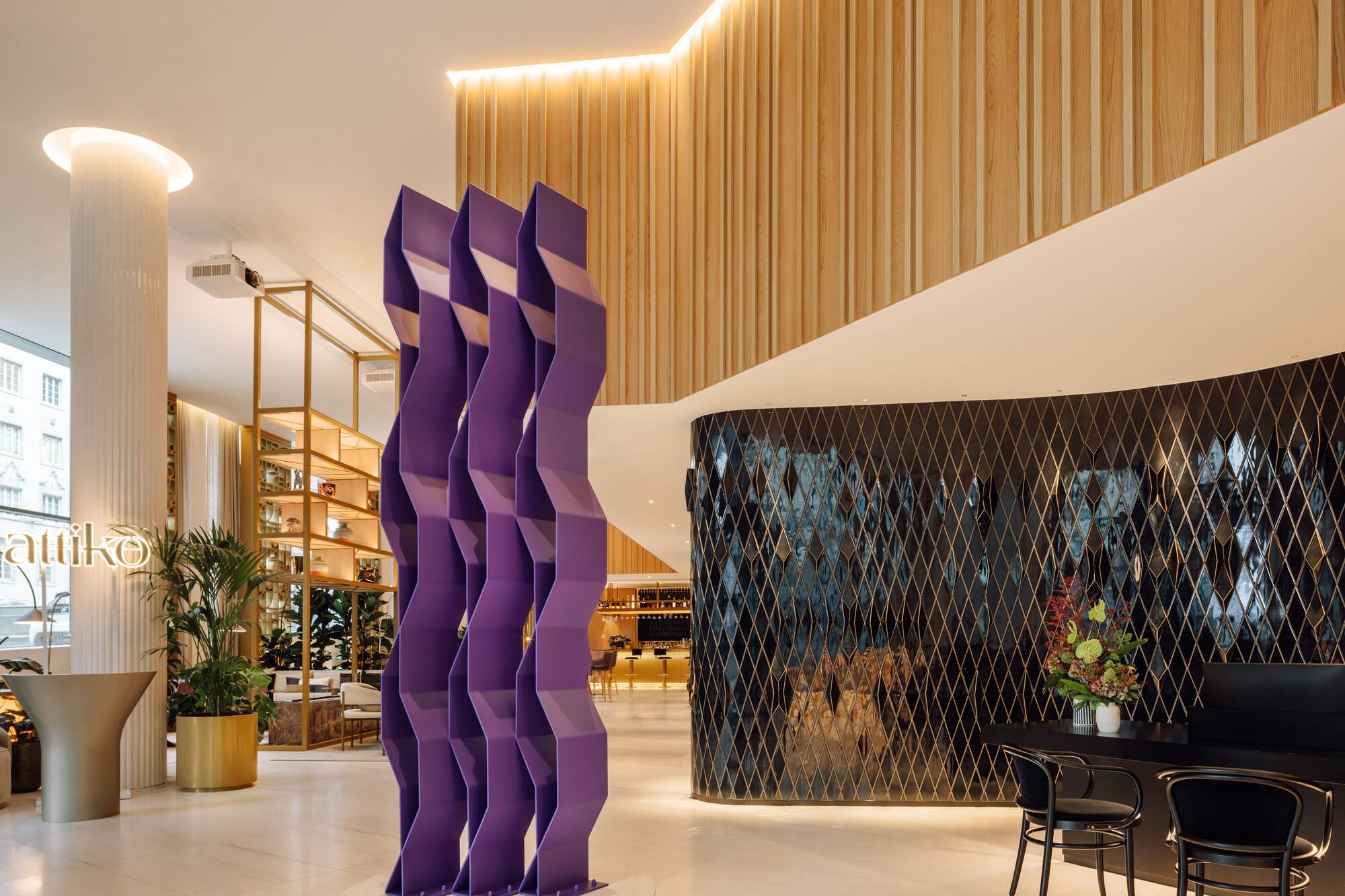 Modern hotel lobby with purple sculpture, wood walls, and black diamond pattern.