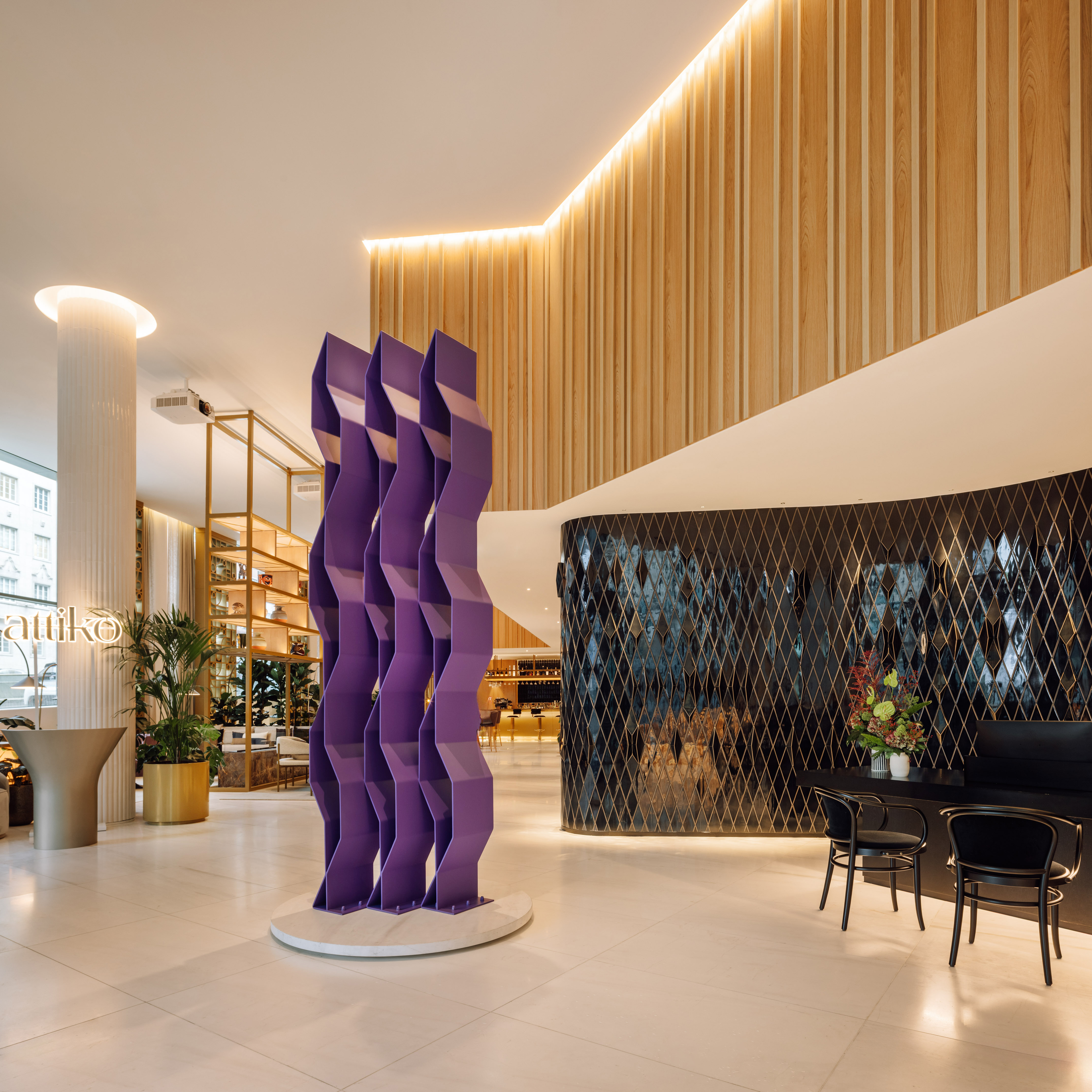 Modern hotel lobby with purple abstract sculpture, wood paneling, and black geometric wall.