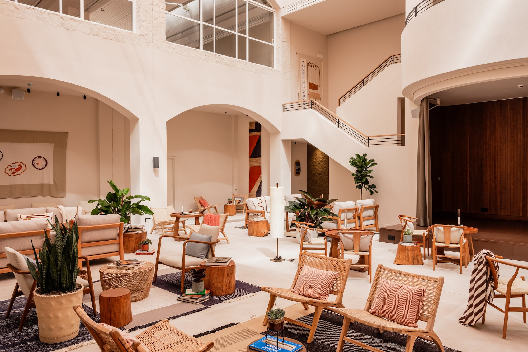 Modern lounge with high ceilings, natural light, wooden and rattan furniture.