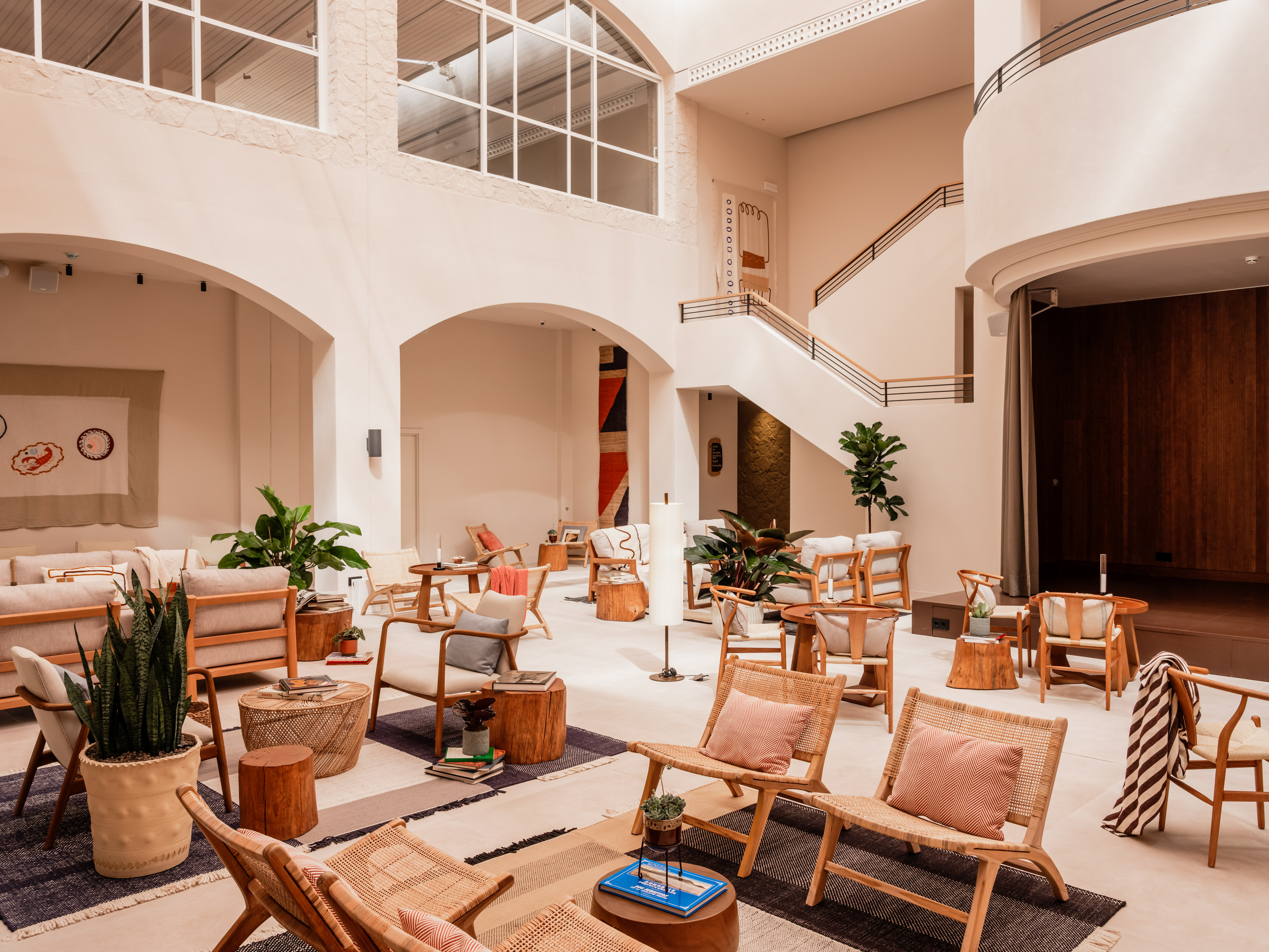 Modern lounge with high ceilings, natural light, wooden and rattan furniture.