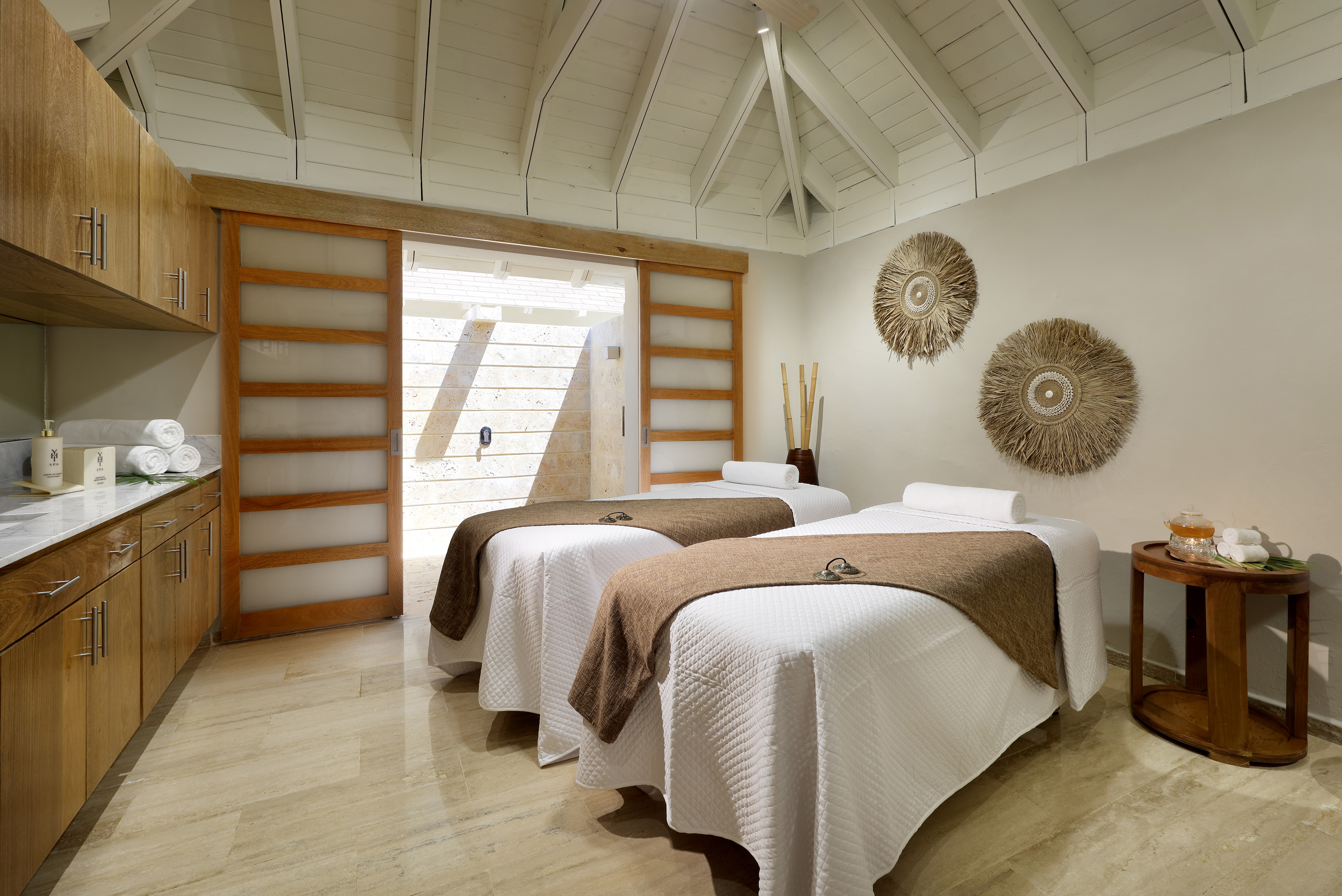 Luxury spa room with two massage beds, vaulted ceiling, and serene ambiance.