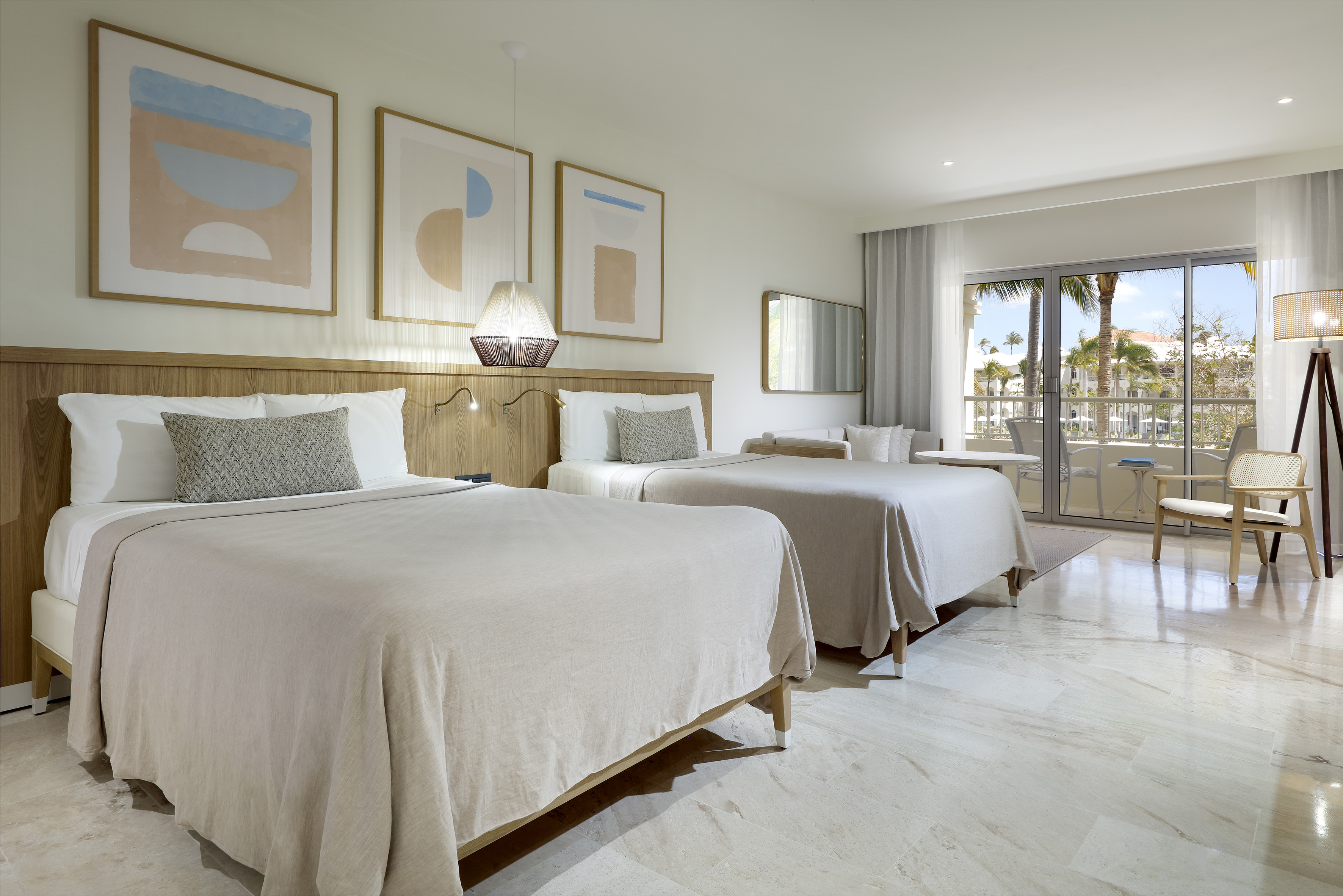 Modern resort room with two beds, balcony, and tropical view.