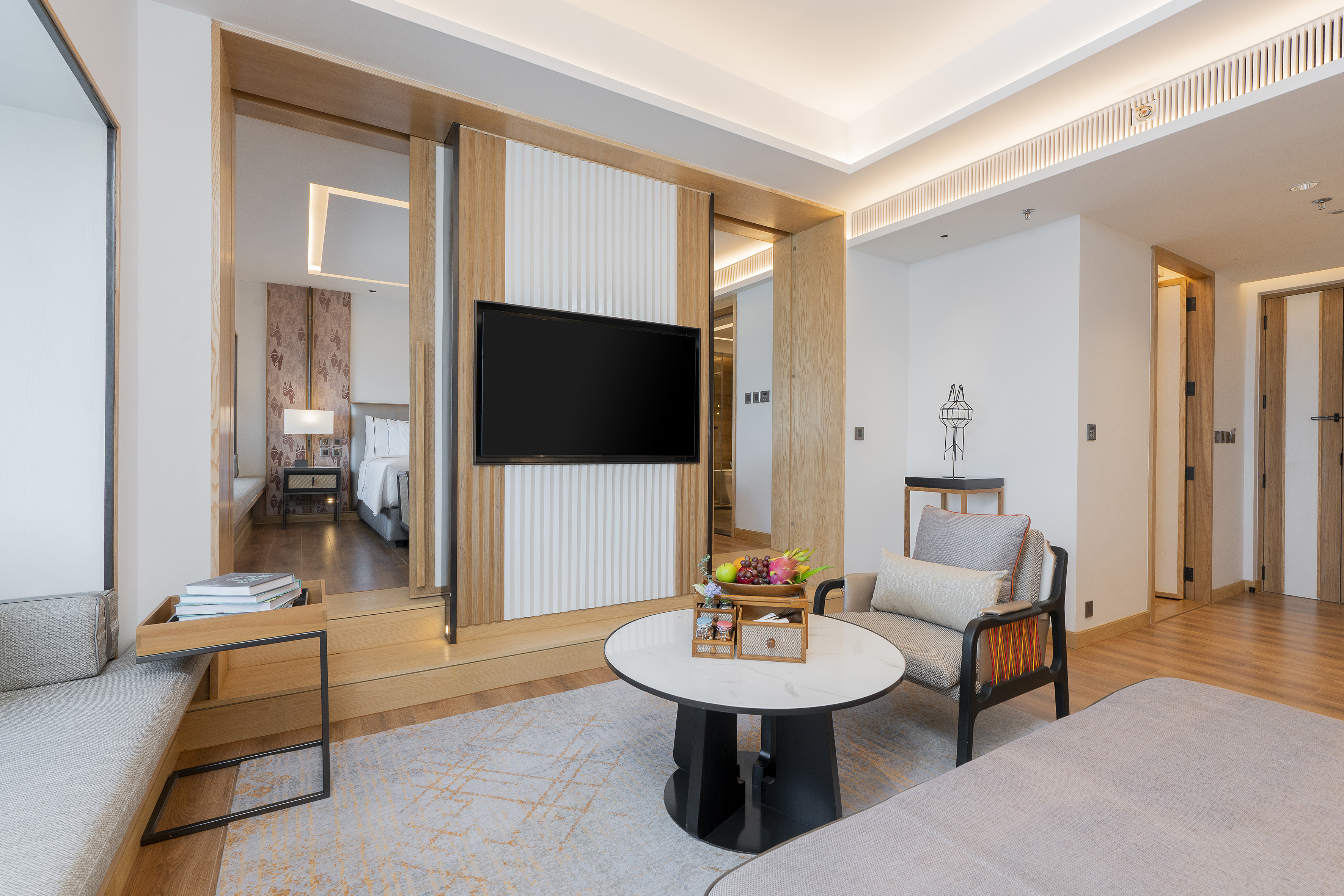 Luxury hotel suite with modern living area, TV, and adjoining bedroom.