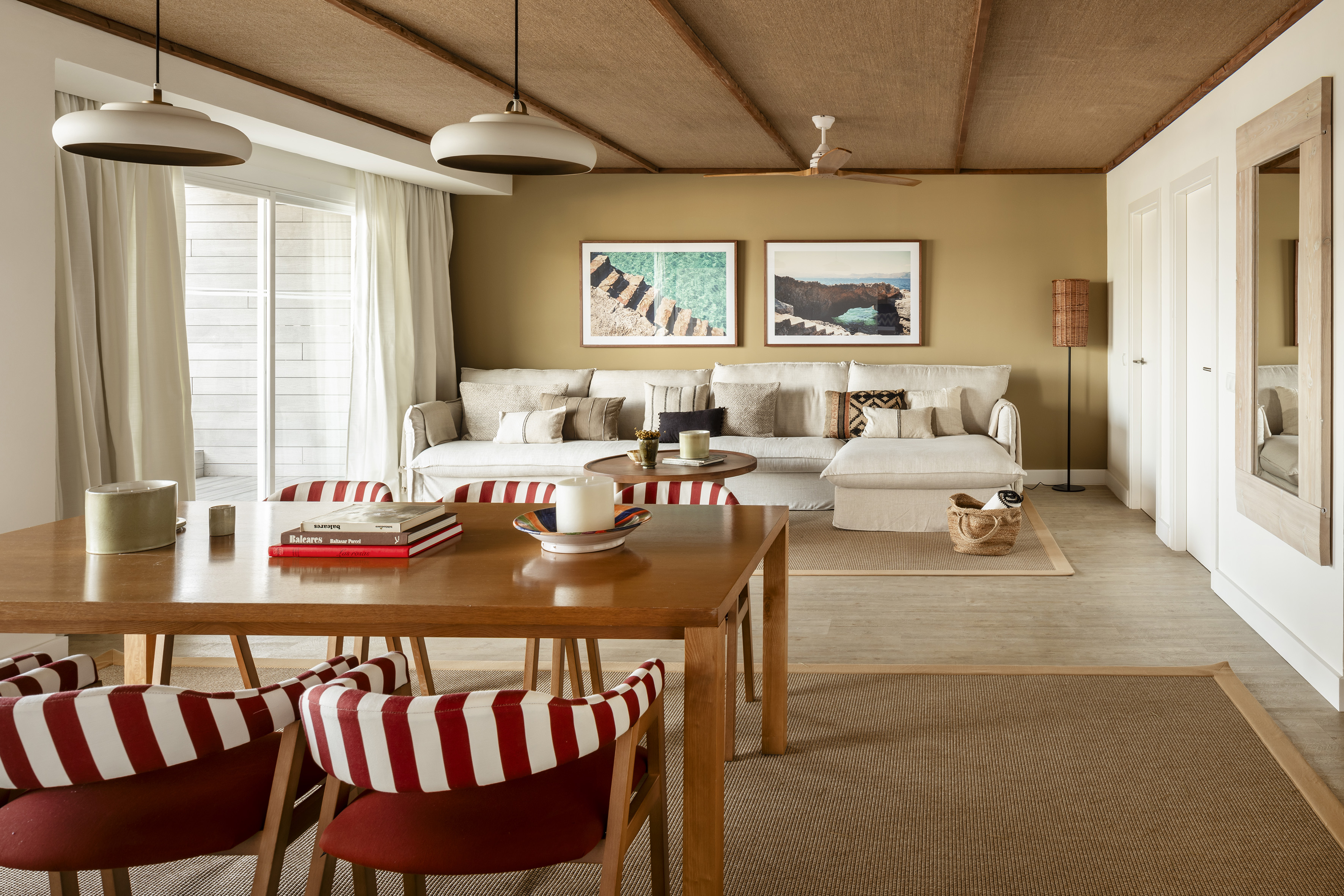 Coastal living-dining room with striped chairs, beige sofa, and woven ceiling.