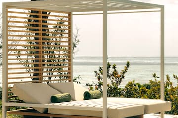 a lounge chair with a canopy on a patio overlooking the ocean