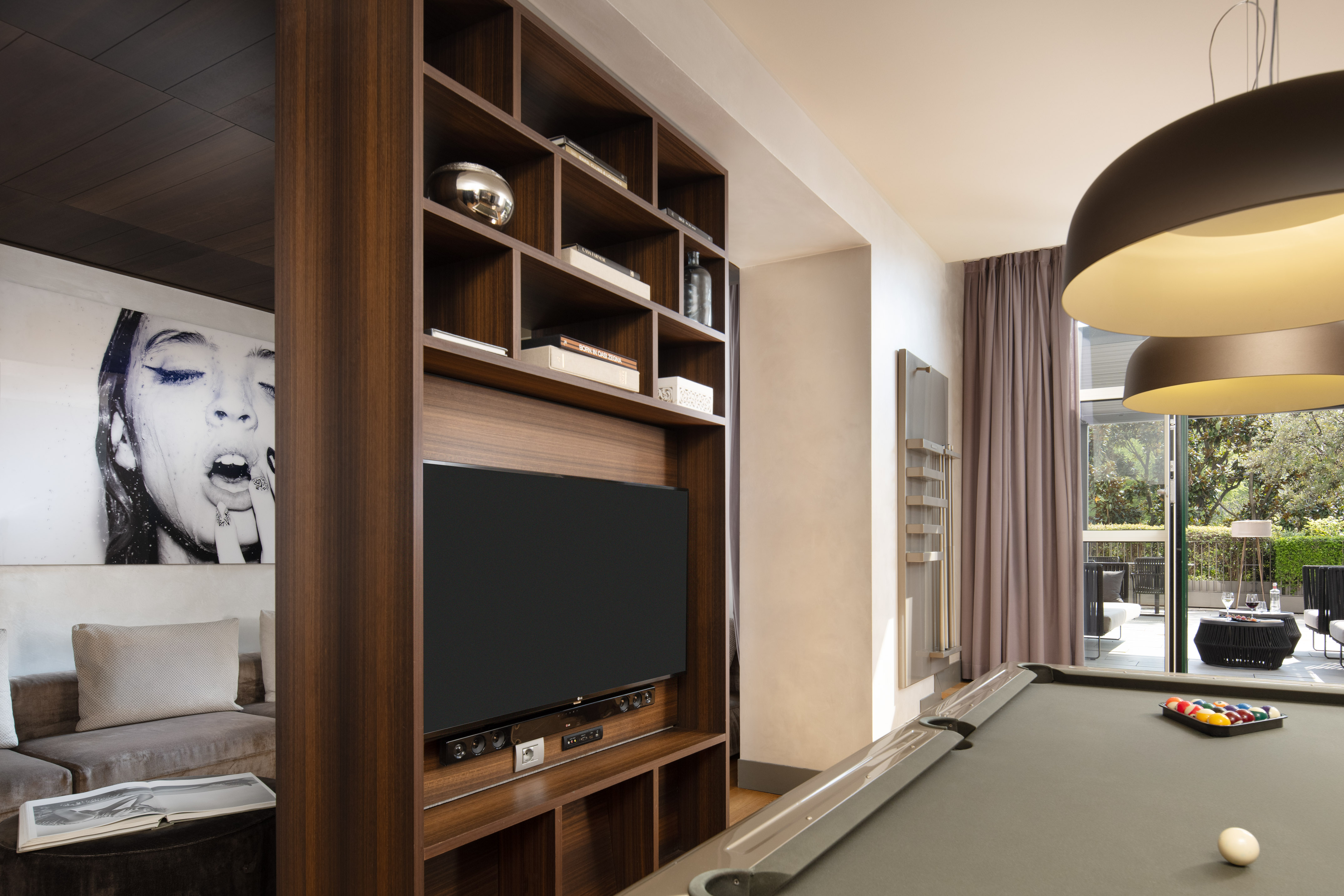 Luxury entertainment room with wood media center, TV, and billiards table.