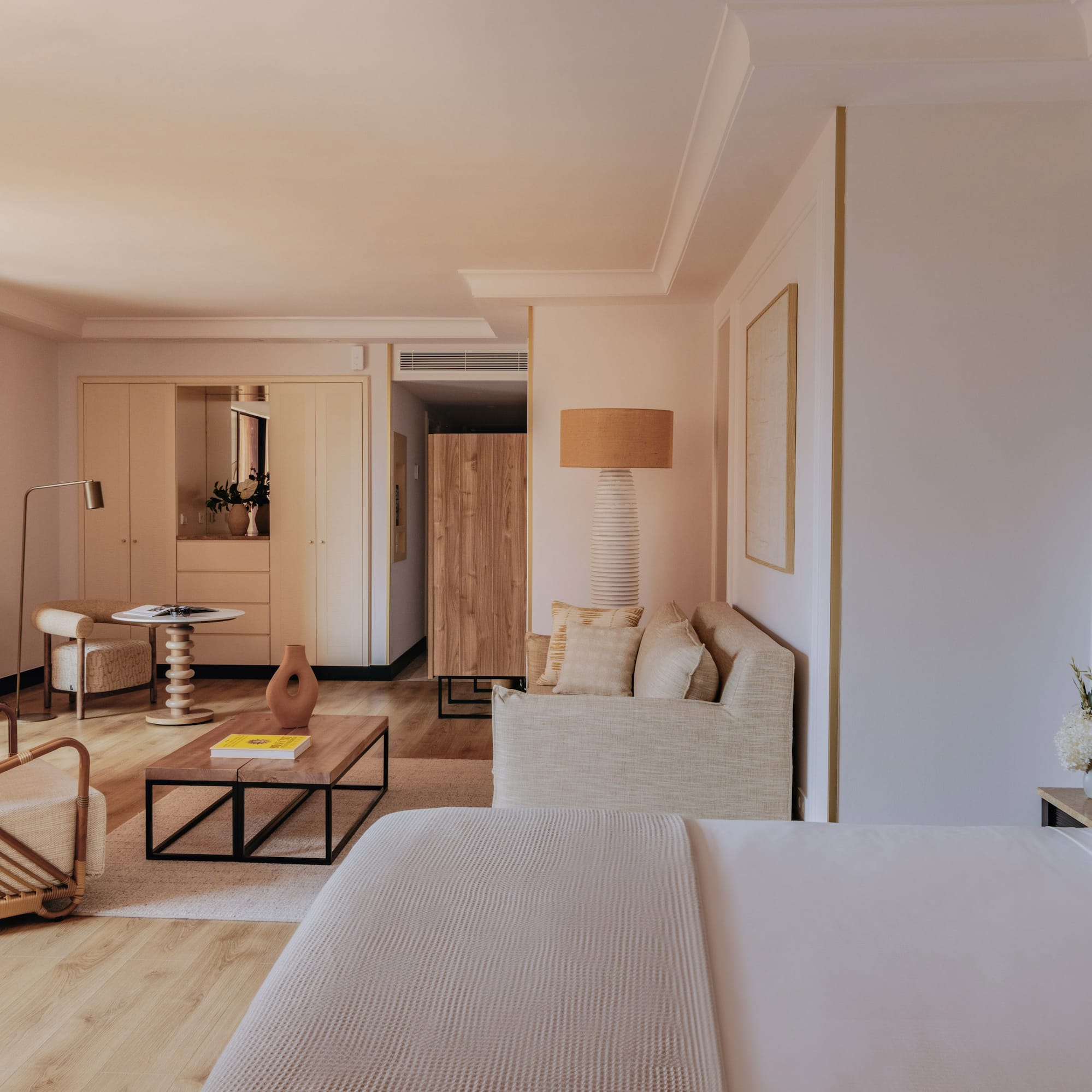 Elegant hotel suite with bed, modern living area, and natural wood details.