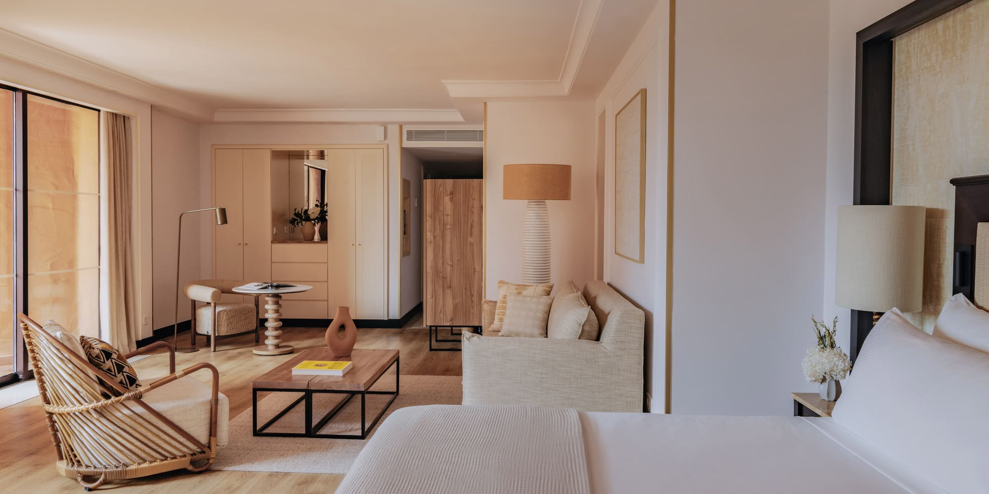 Elegant hotel suite with bed, modern living area, and natural wood details.