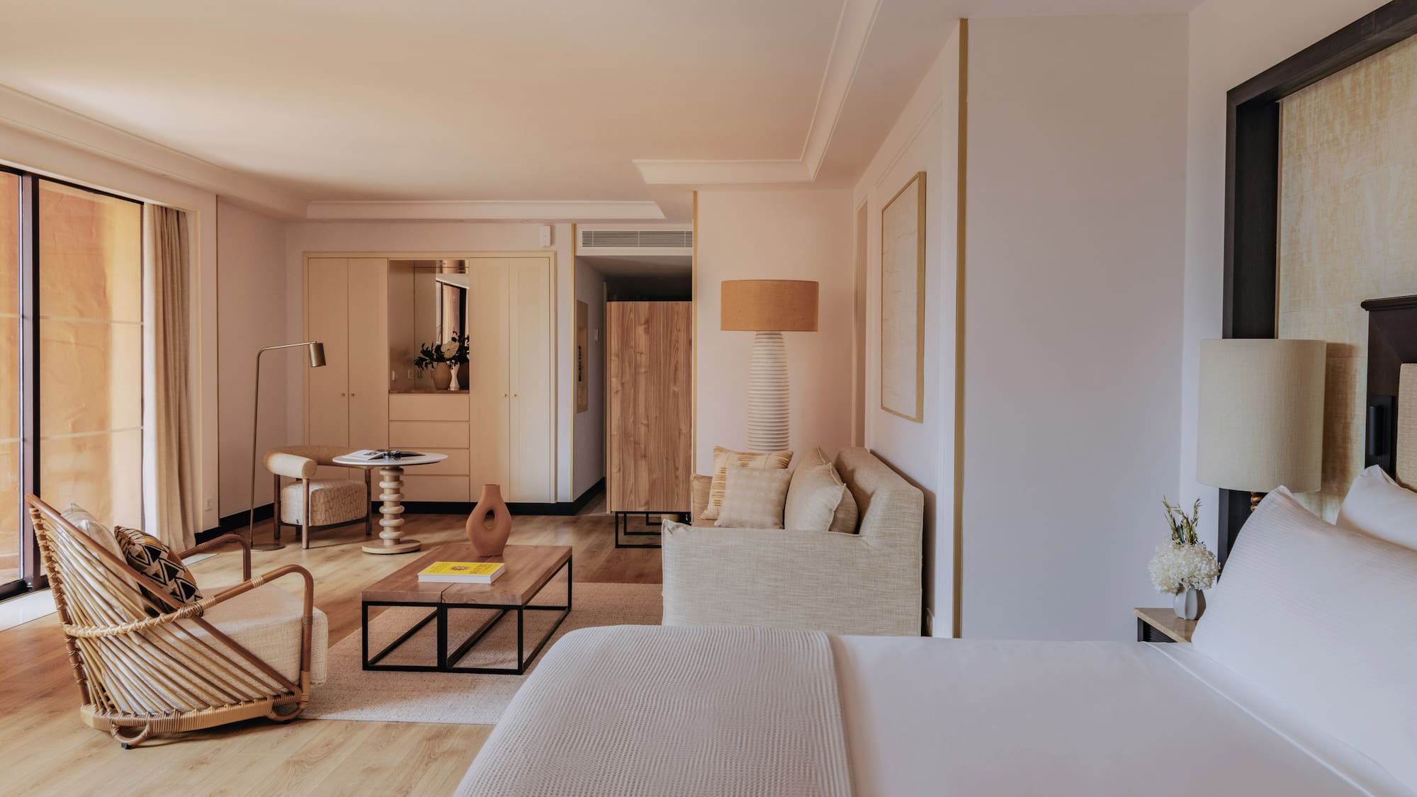 Elegant hotel suite with bed, modern living area, and natural wood details.