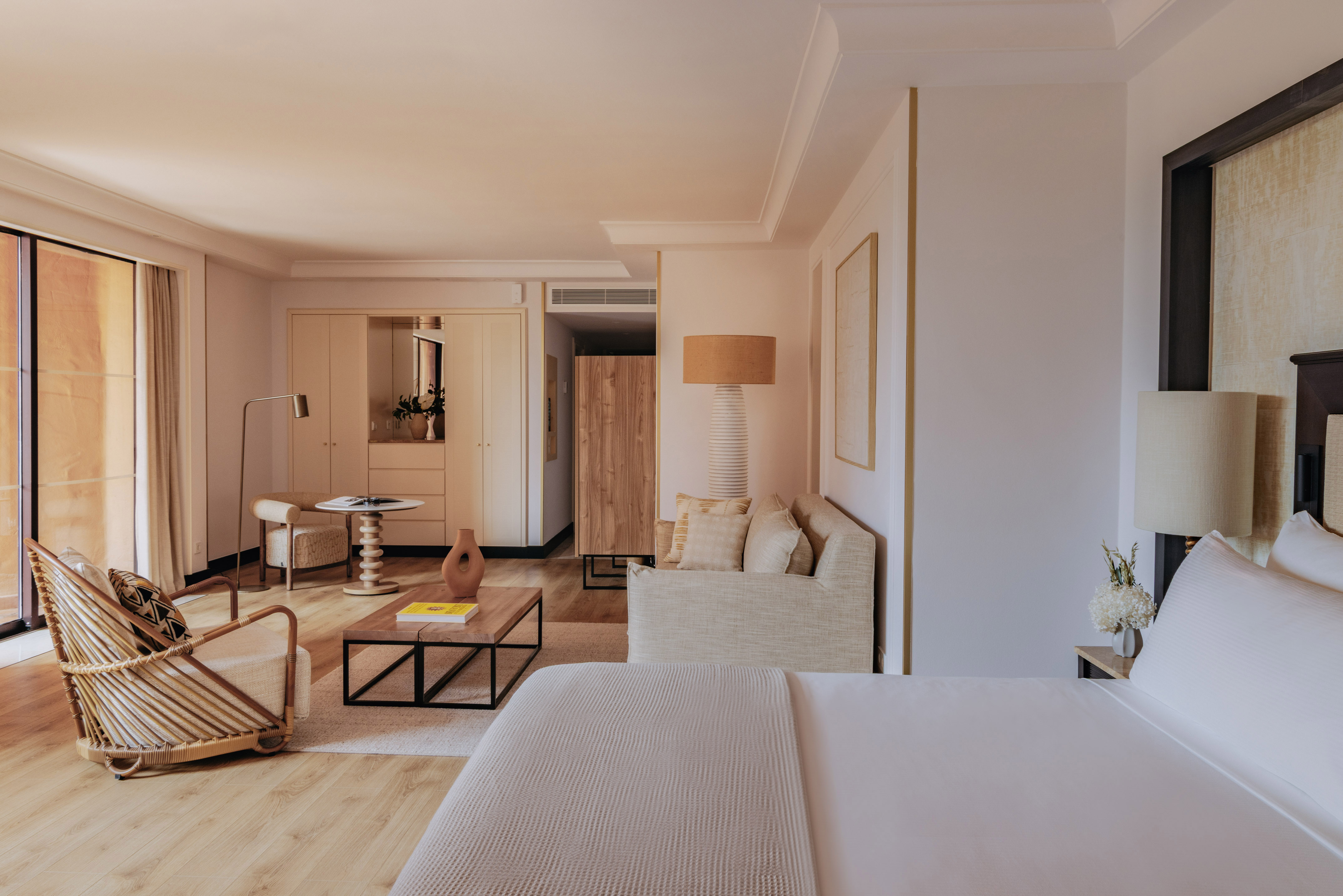 Elegant hotel suite with bed, modern living area, and natural wood details.