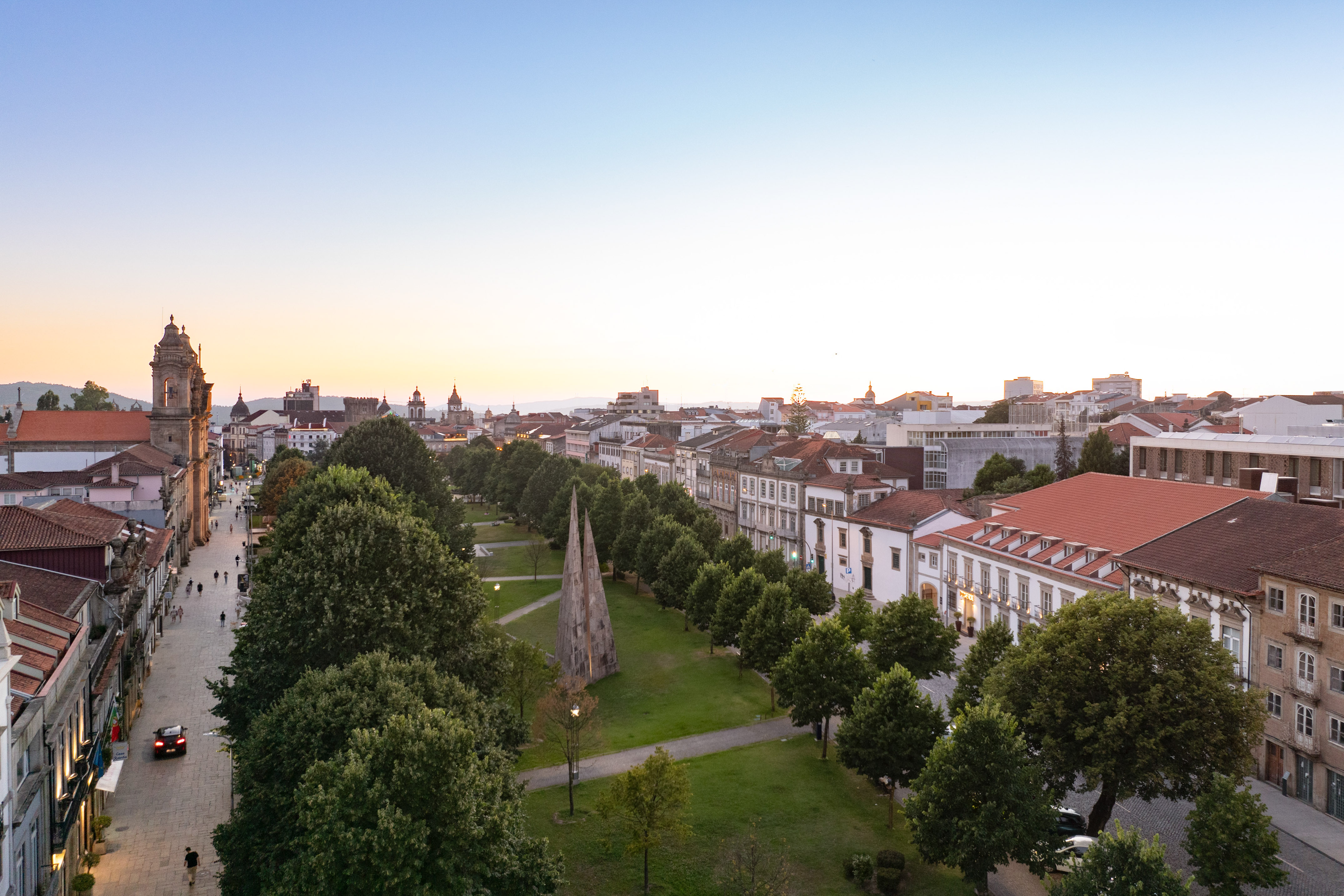 Guimarães, Portugal city park and historic buildings along a street at dusk.