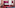 Colorful hotel bedroom with magenta wall, red carpet, blue bed, and pink desk.