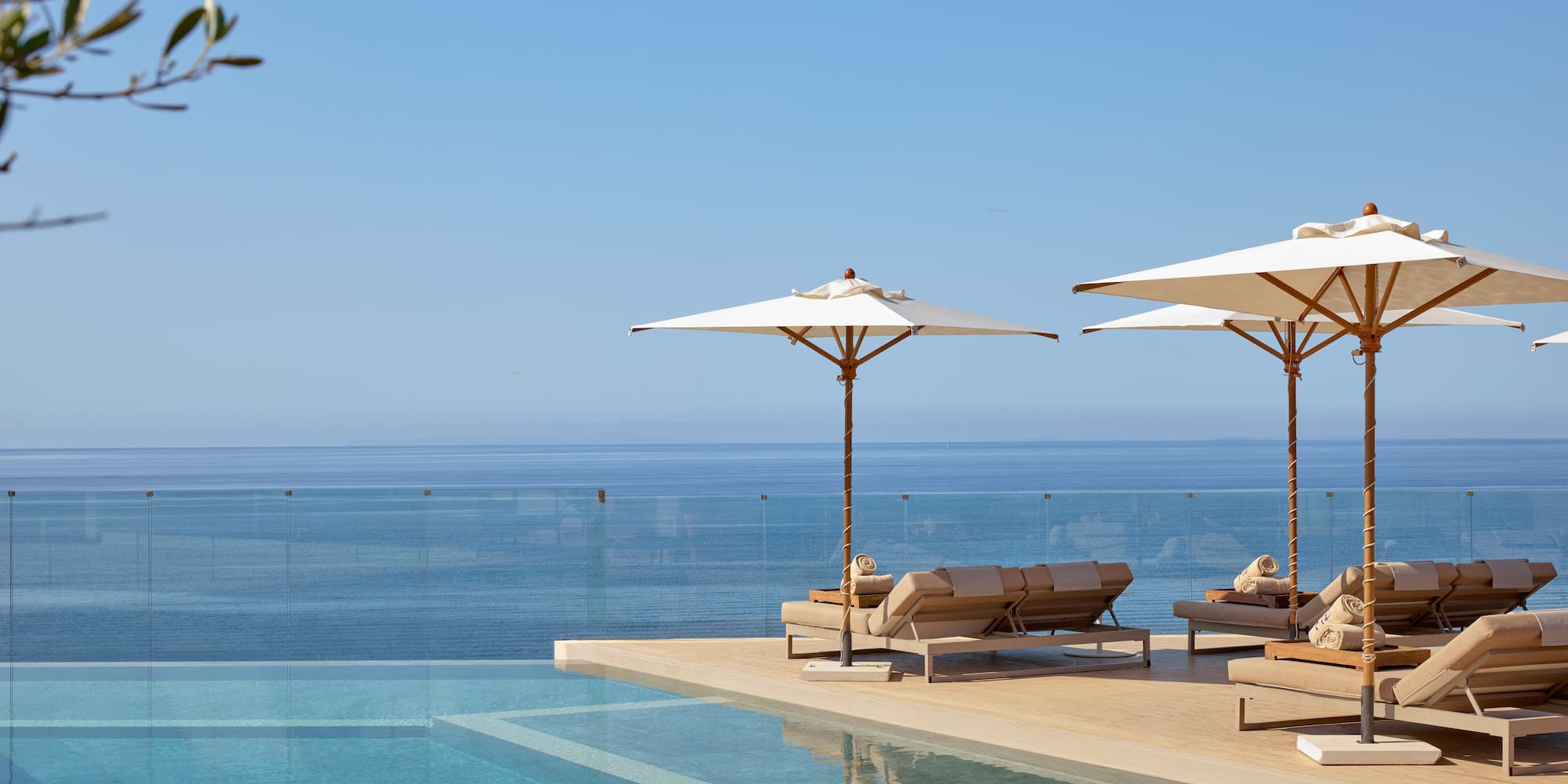 Luxury infinity pool with sun loungers, umbrellas, and ocean view.