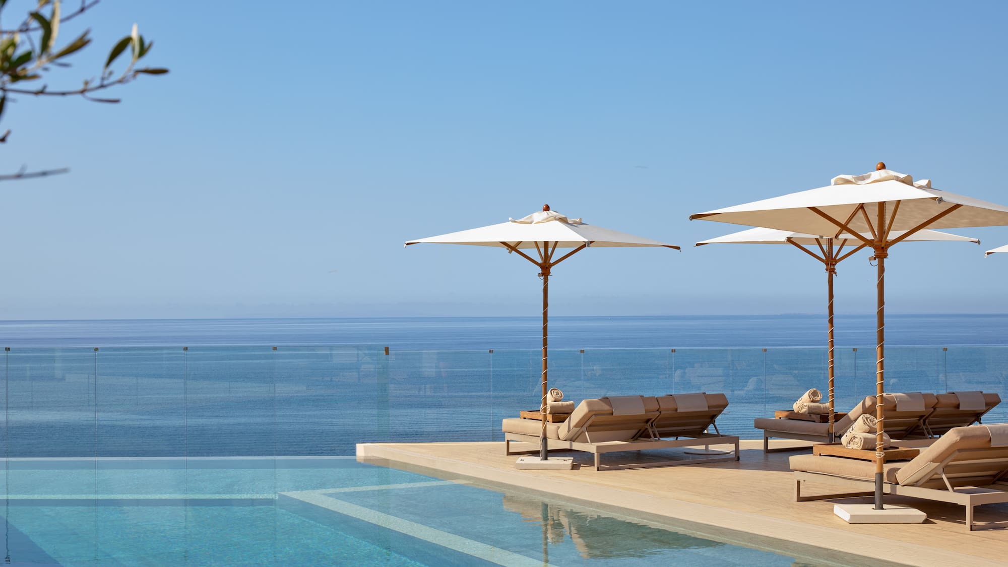 Luxury infinity pool with sun loungers, umbrellas, and ocean view.