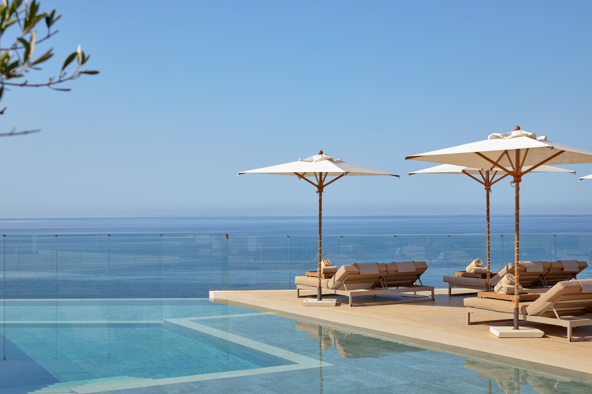 Luxury infinity pool with sun loungers, umbrellas, and ocean view.